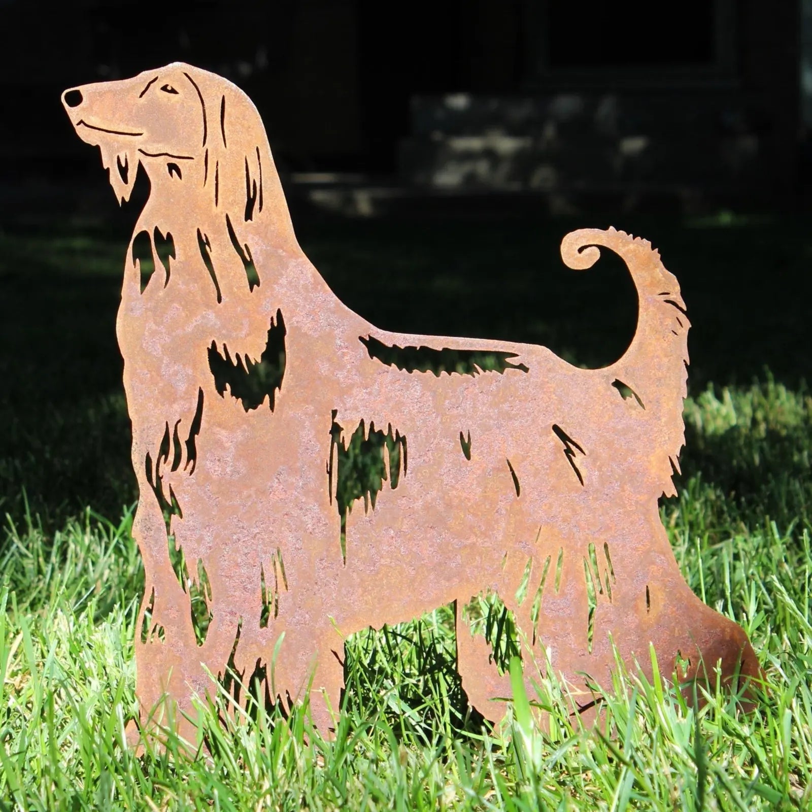 Afghan Hound metal silhouette in rusty Corten steel, set in green grass, showcasing intricate detailing and design.