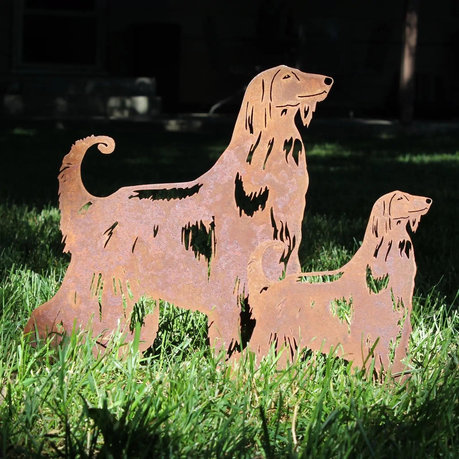 Rusty Corten steel Afghan Hound silhouettes displayed on green grass, depicting a standing and a sitting dog.