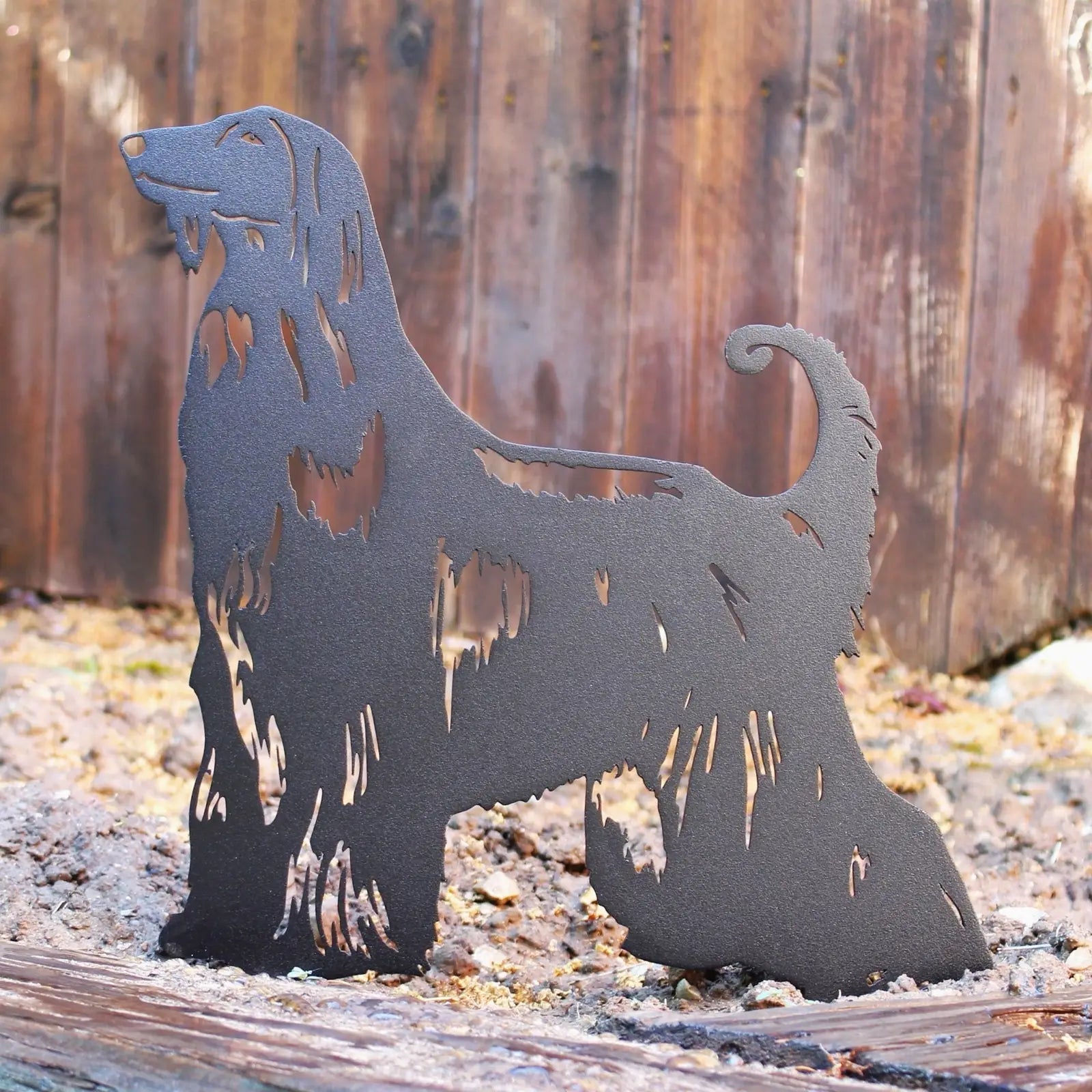Black metal silhouette of an Afghan Hound, detailed with cutouts, set against a rustic wooden backdrop.