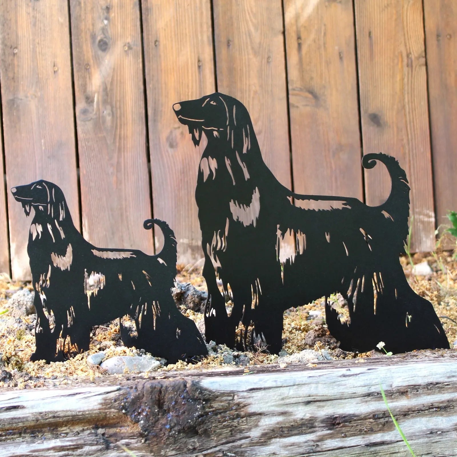 Black metal silhouettes of Afghan Hounds, displayed in a rustic outdoor setting with wooden background and rocks.
