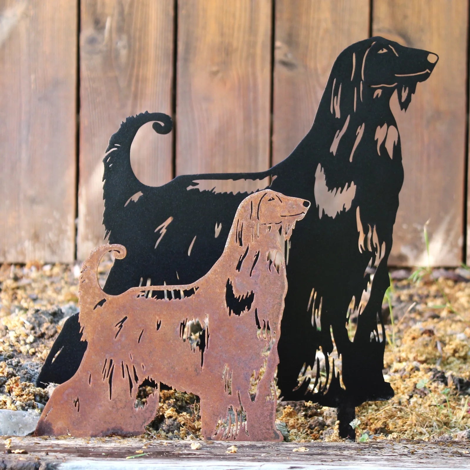 Two Afghan Hound metal silhouettes in contrasting finishes: a matte black and a rusted Corten steel, set against a wooden...