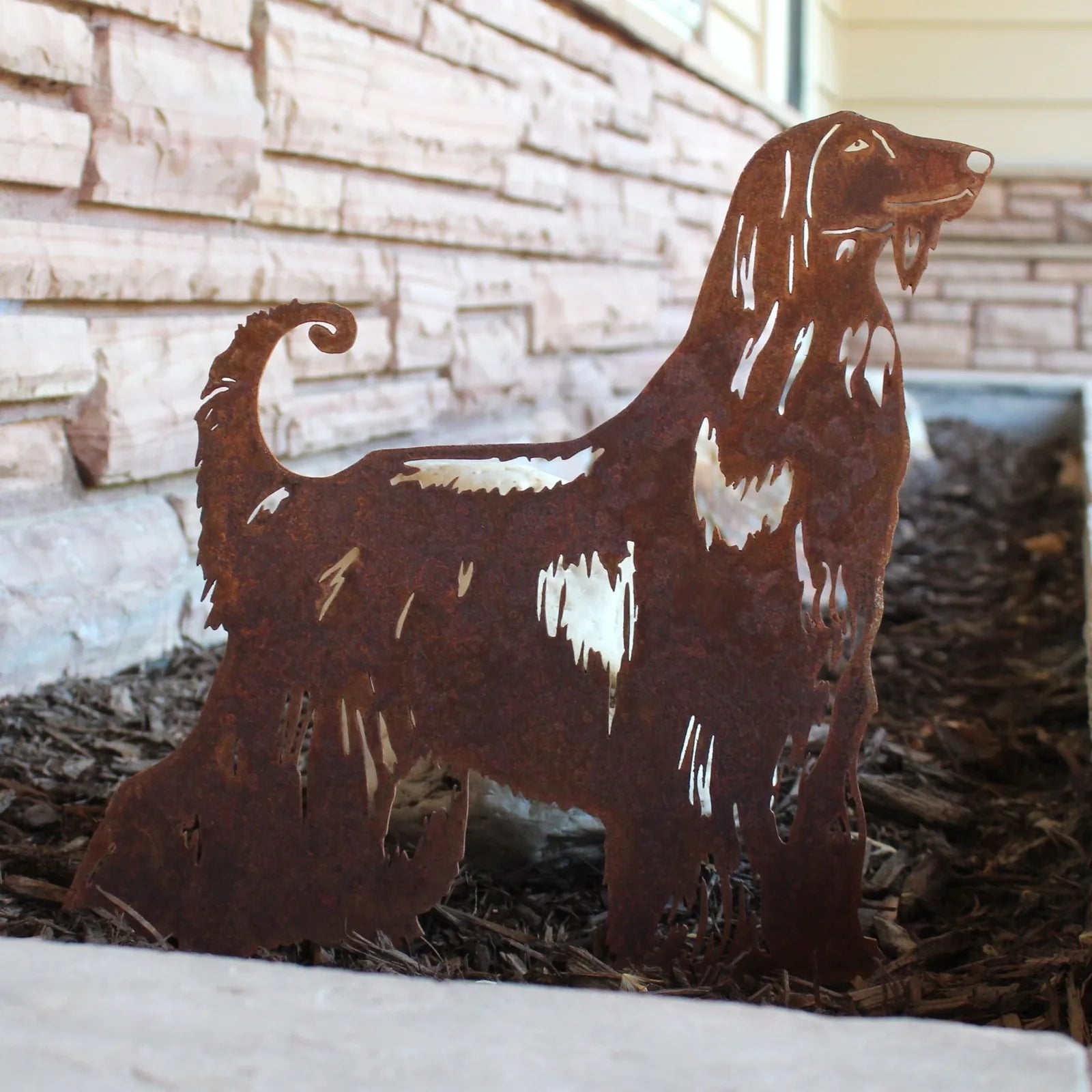 Rusty metal silhouette of an Afghan Hound in a garden setting, showcasing intricate cutouts and a weathered patina.