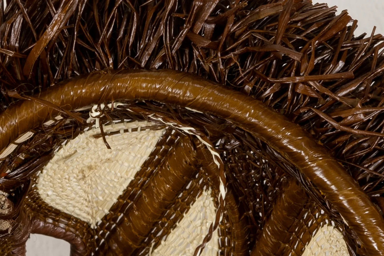 Handwoven African Wild Dog mask close-up, featuring rich brown and beige tones with intricate patterns.