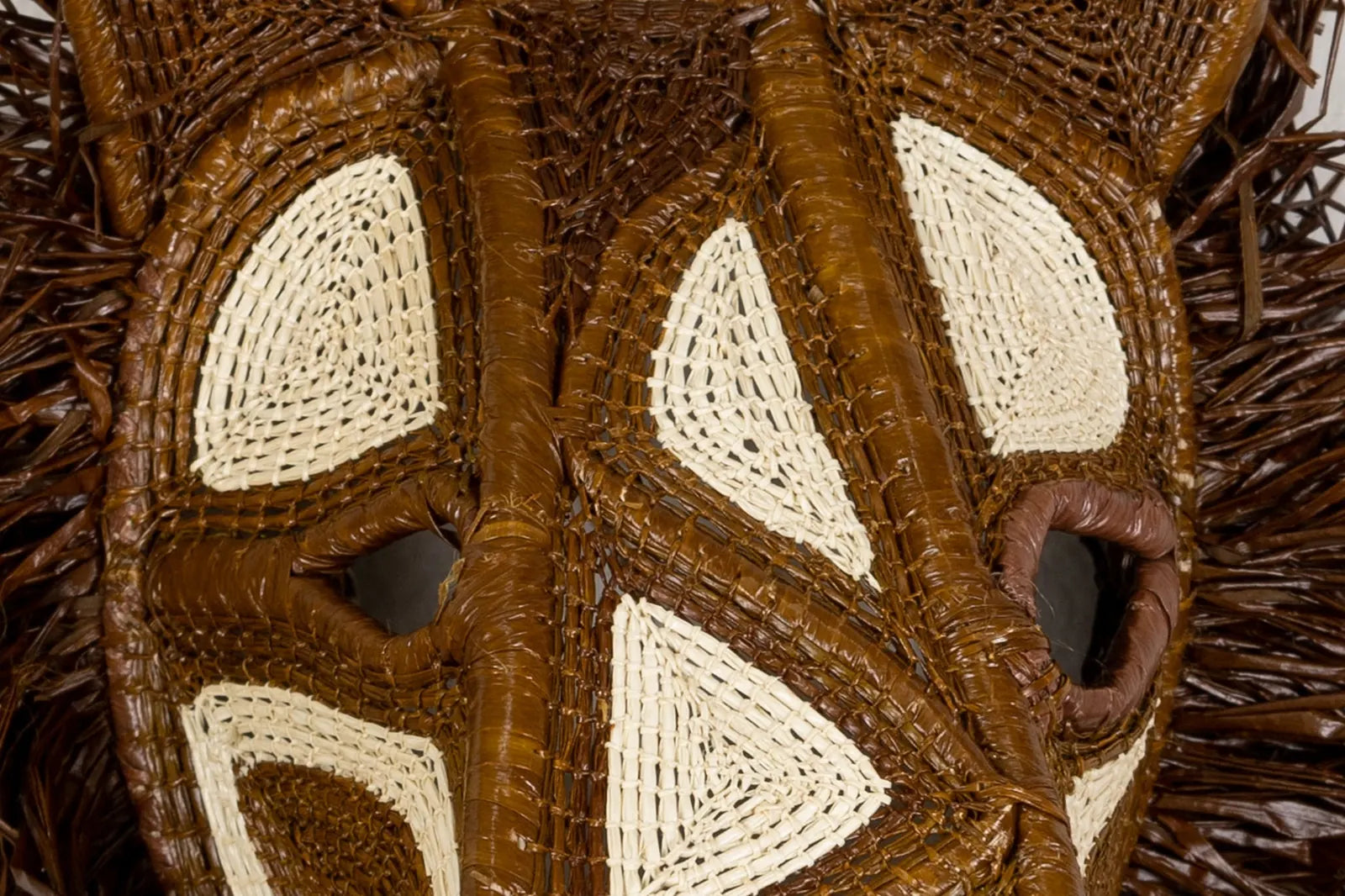 Handwoven African Wild Dog mask featuring rich brown tones and intricate beige patterns, made from natural materials.