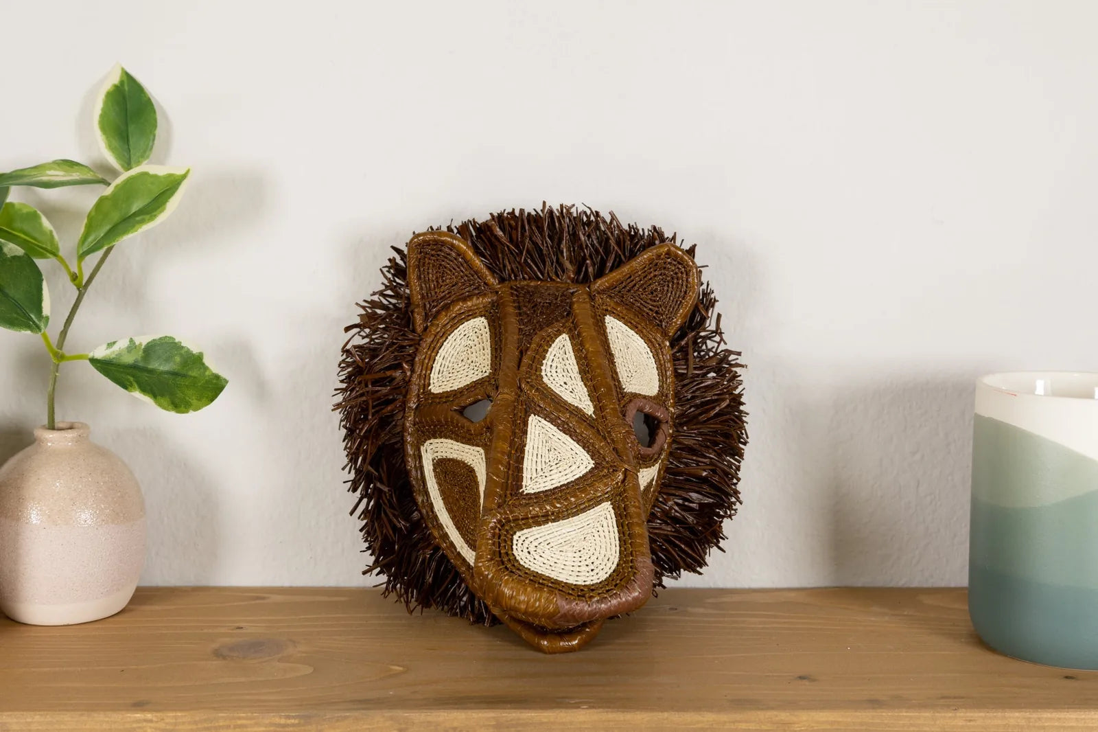 Handwoven African Wild Dog mask featuring brown hues and intricate patterns, adorned with textured natural materials.