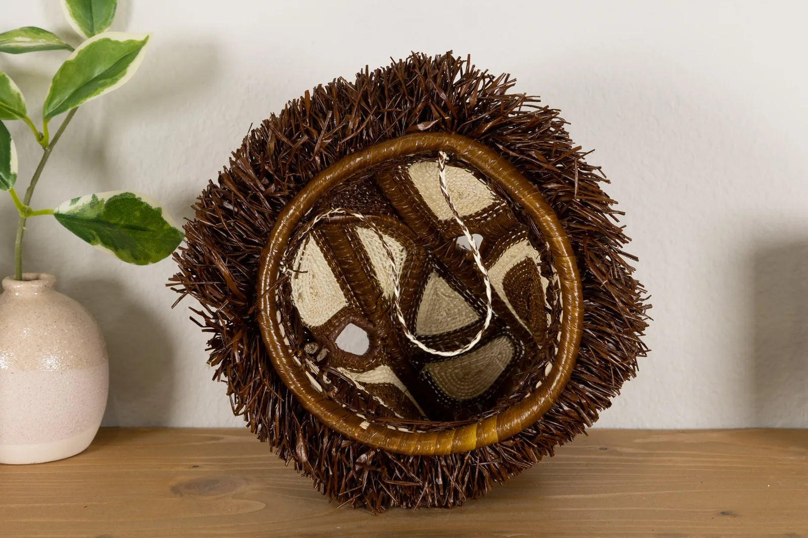 Handwoven African Wild Dog mask in earthy browns with intricate patterns, showcasing natural materials and artisan craftsm...