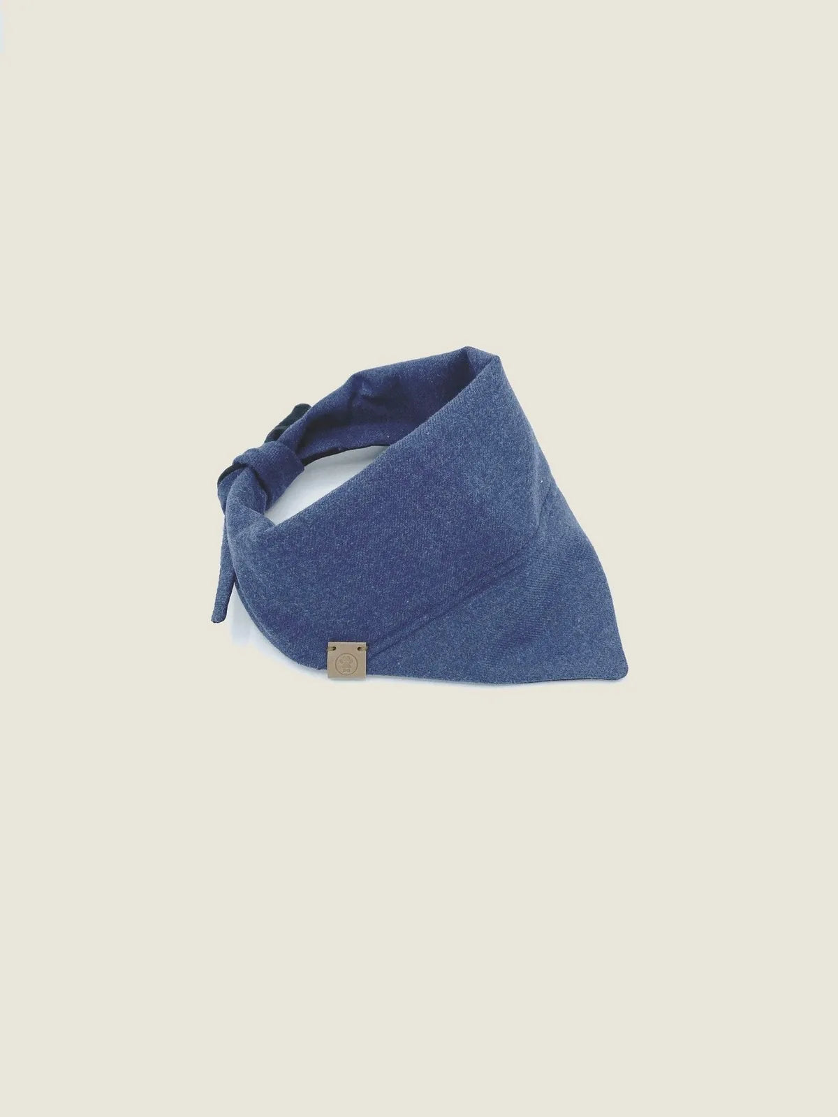 Reversible navy blue pet bandana with soft cotton flannel and adjustable tie design, featuring a branded tag.