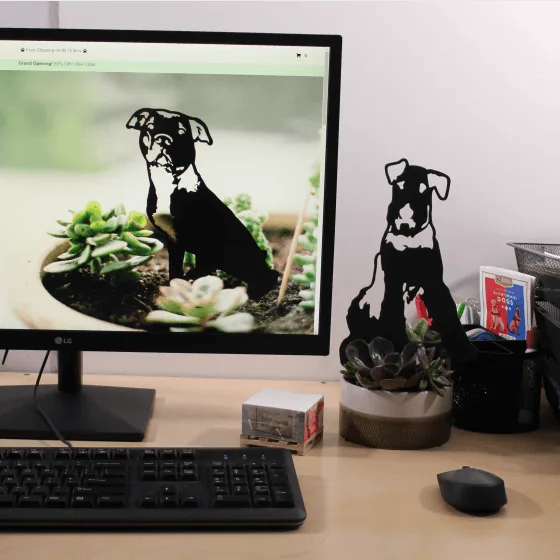Black Airedale Terrier metal silhouette by My Metal Rescue beside a computer on a desk with succulents in the background.