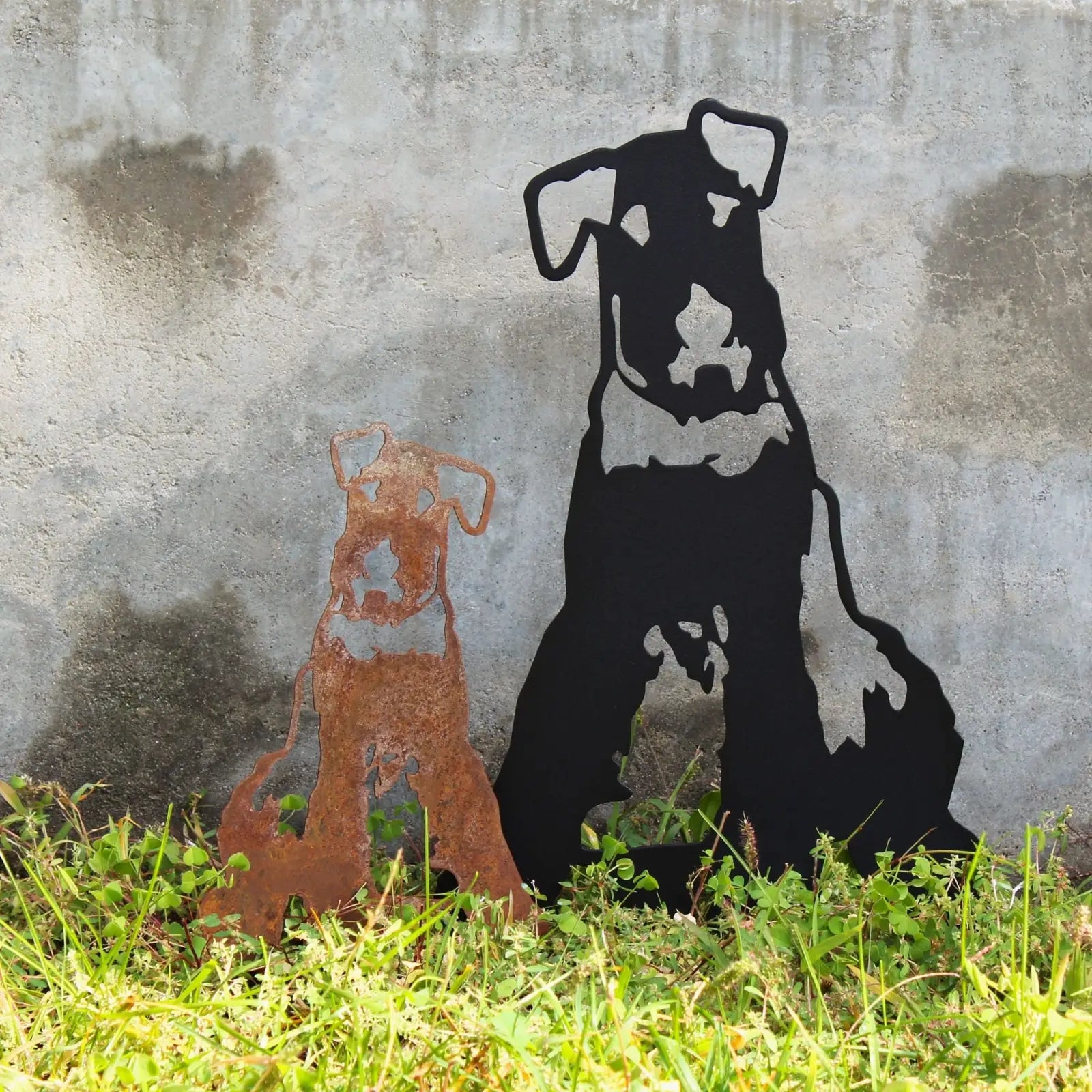 Airedale Terrier metal silhouettes in rusted Corten steel and matte black, displayed against a concrete backdrop.