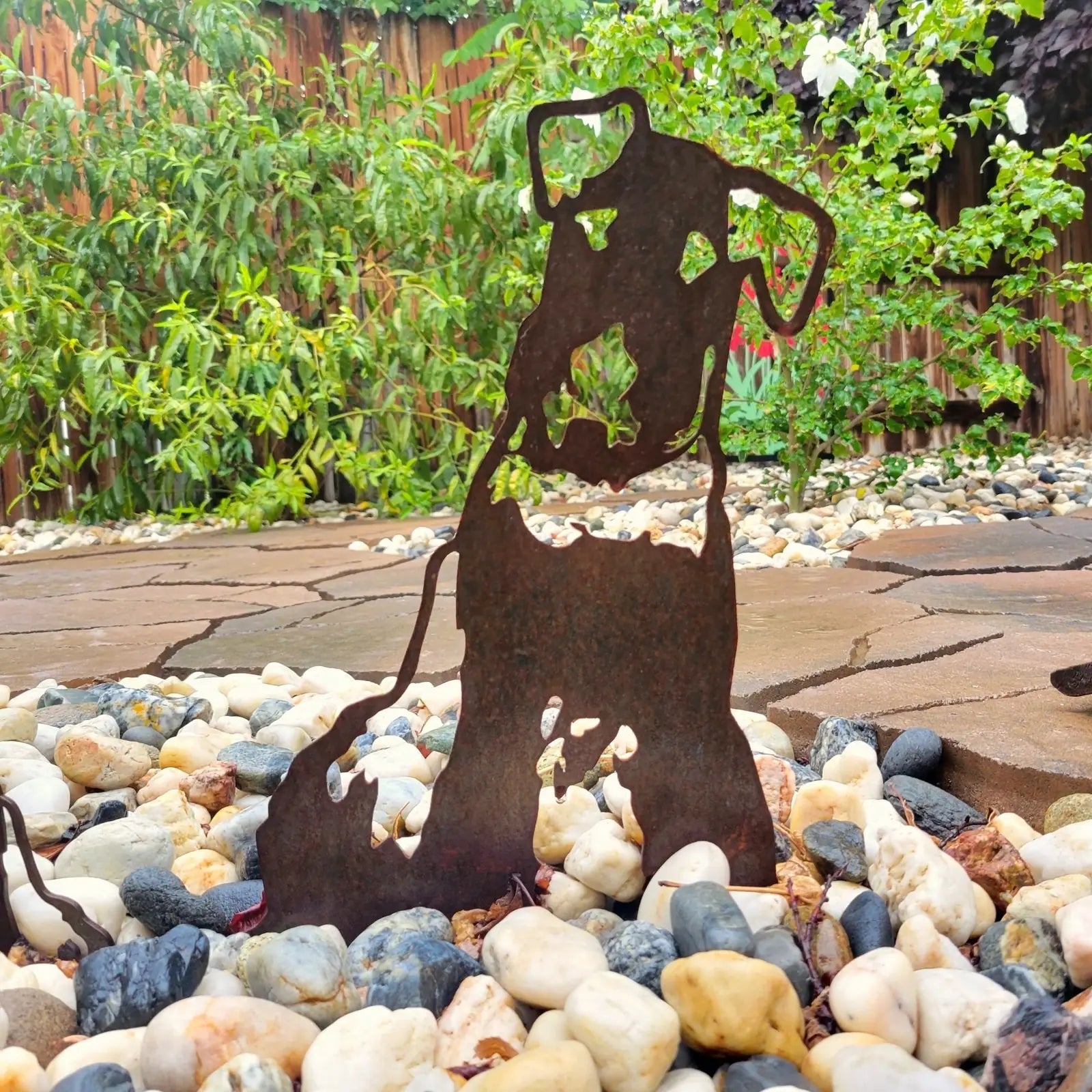 Airedale Terrier silhouette in rusted Corten steel amid pebbles, enhancing outdoor dog decor with a natural look.