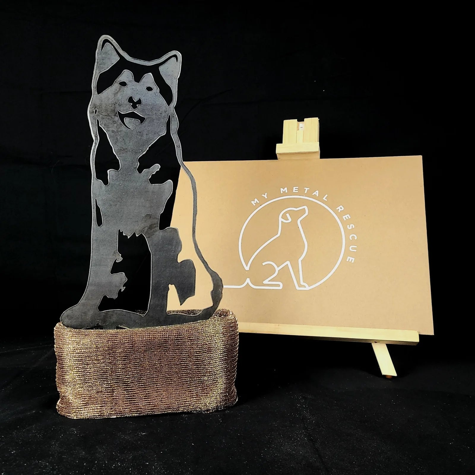 Alaskan Malamute metal silhouette in a matte black finish, mounted on a rustic base, showcasing dog-themed outdoor decor.