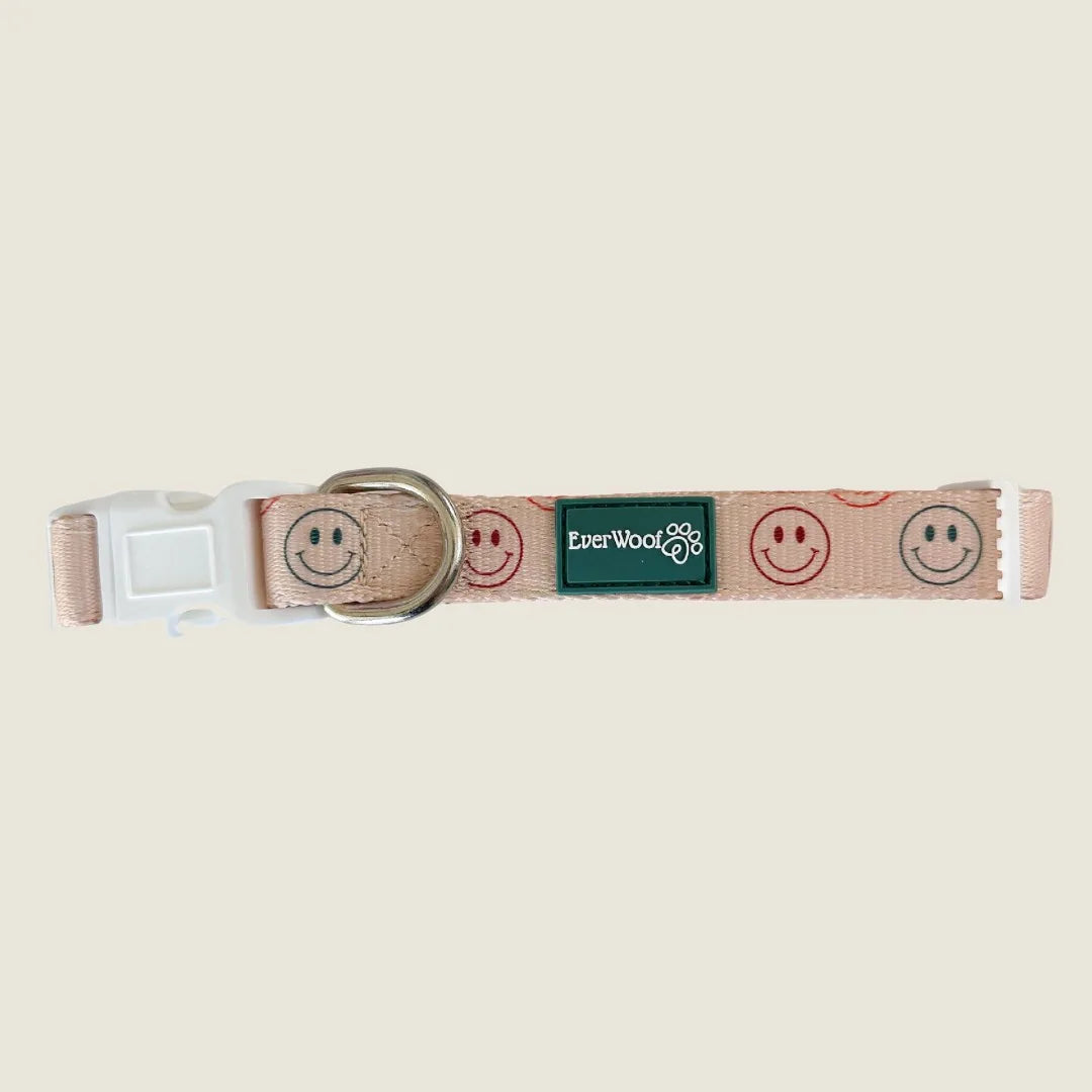 Light pink adjustable dog collar featuring cheerful smiley face prints, made with neoprene padding and polyester webbing.