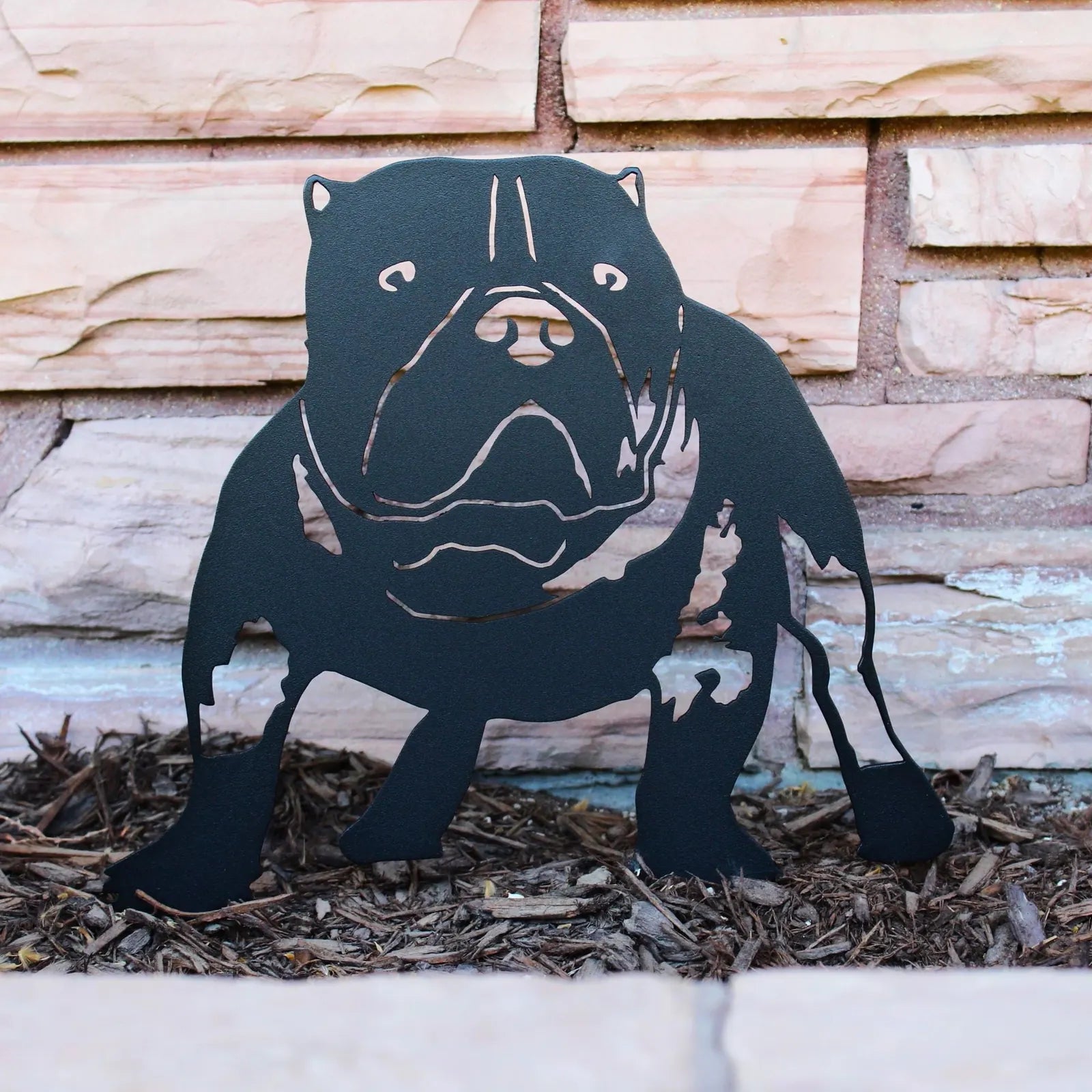 Black metal silhouette of an American Bully dog, positioned against brick, showcasing intricate cut-out details.