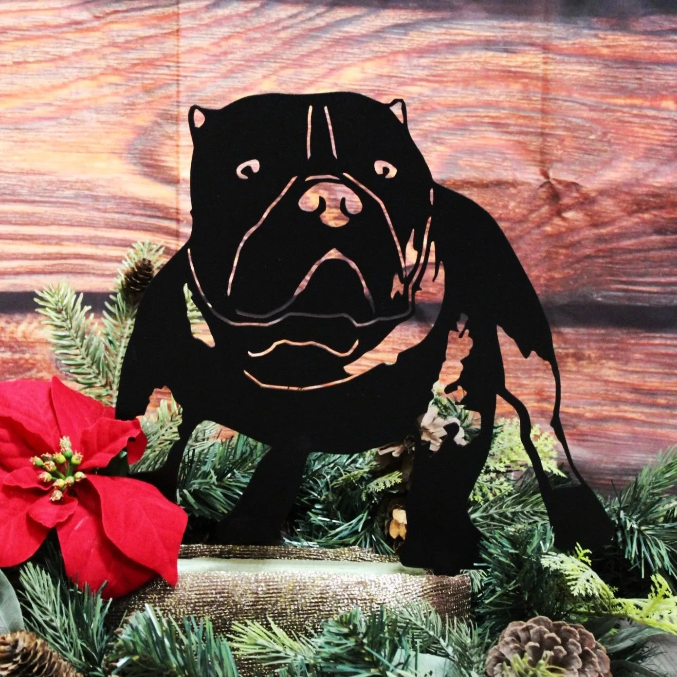 Black metal American Bully silhouette art displayed among holiday greenery and a red poinsettia flower.