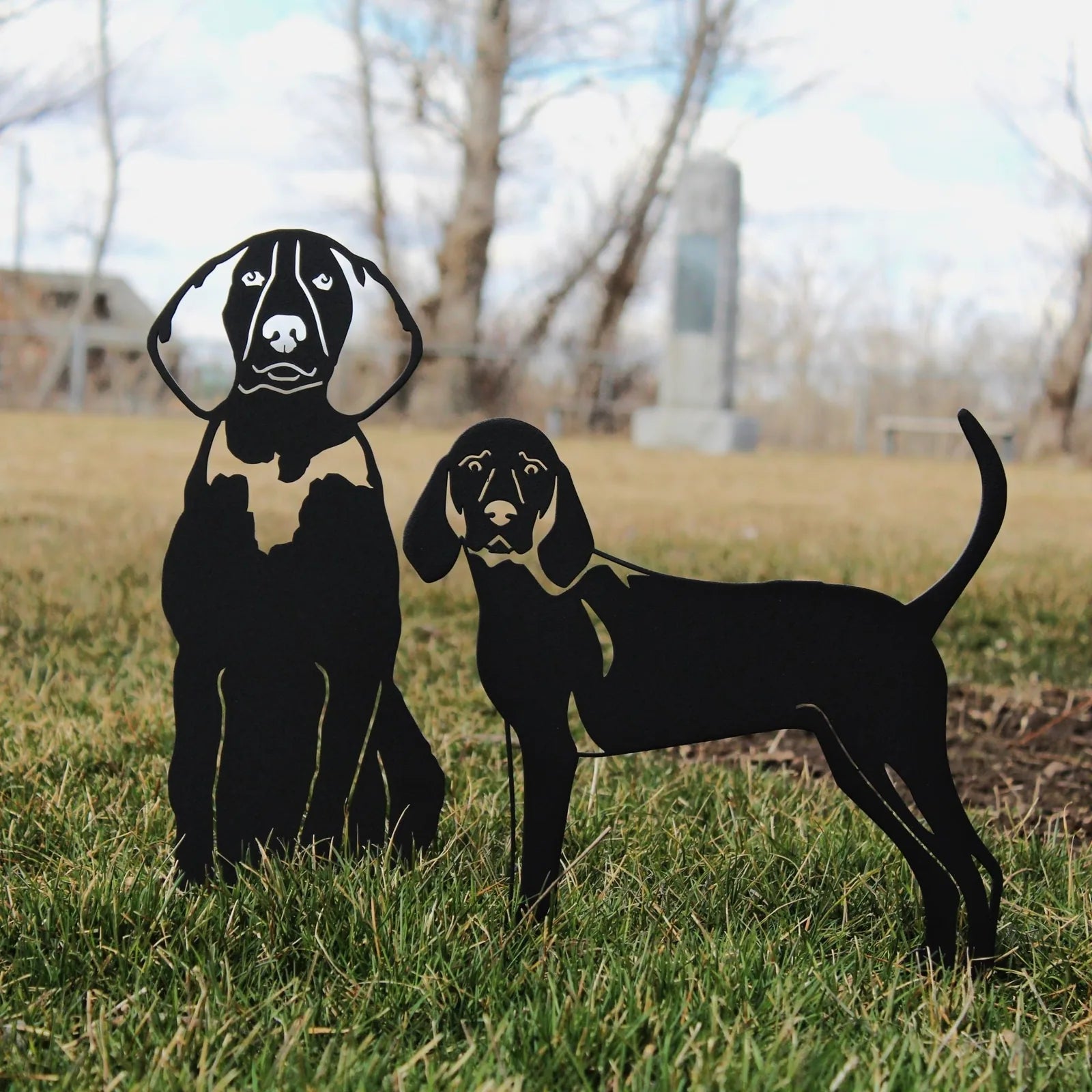 Handmade black metal silhouettes of American English Coonhounds standing on green grass, showcasing their distinctive feat...