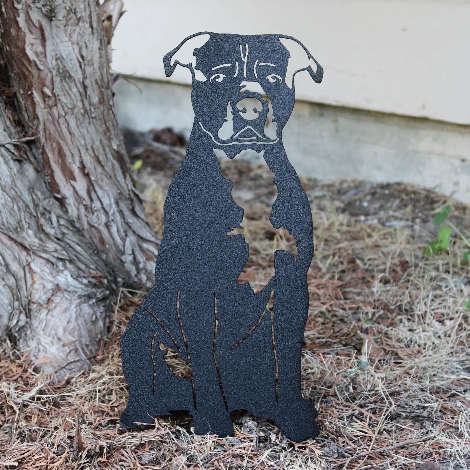Black metal silhouette of an American Staffordshire Terrier sitting beside a tree, showcasing handcrafted dog décor.
