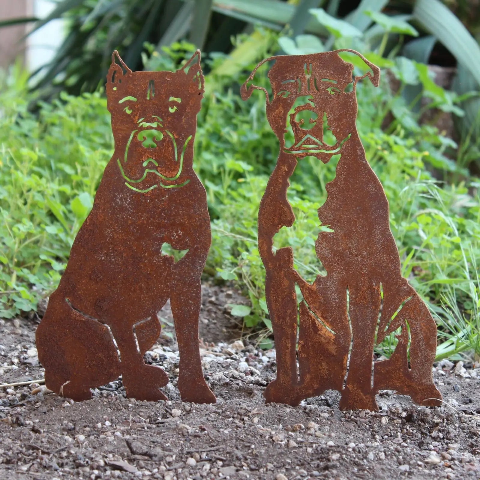Rusty metal silhouettes of American Staffordshire Terriers, handcrafted for dog décor, set among greenery.