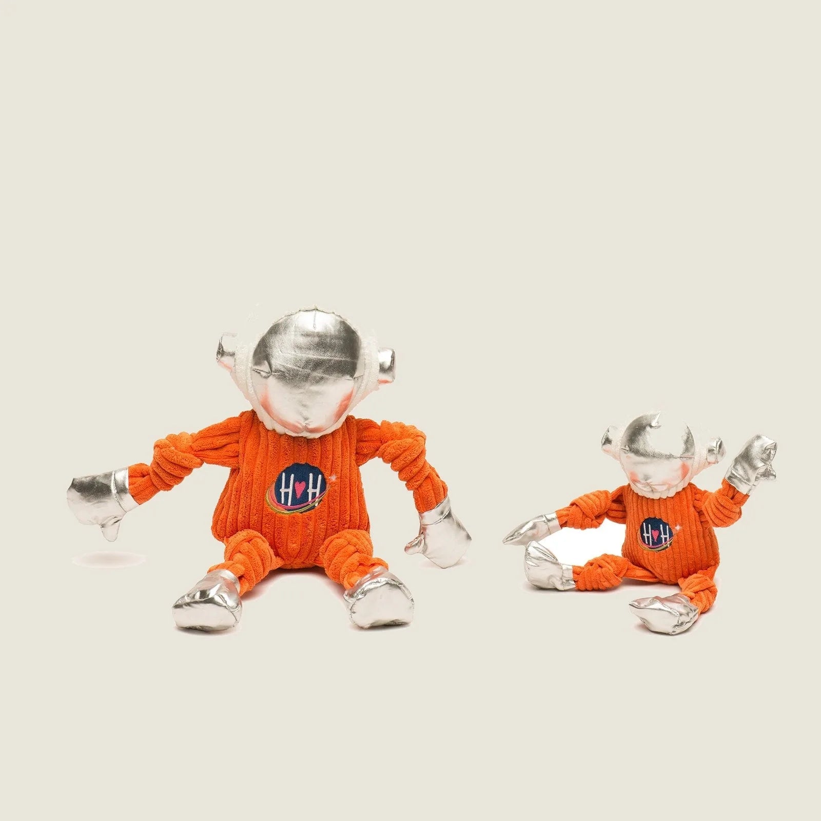 Astro-Knottie® dog toys in bright orange space suits with silver accents, designed for durable play and snuggling.