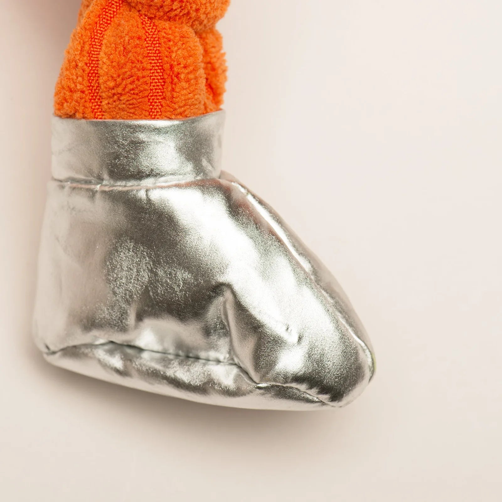 Bright orange dog toy with plush knotted limbs and shiny silver boot, perfect for interactive play.