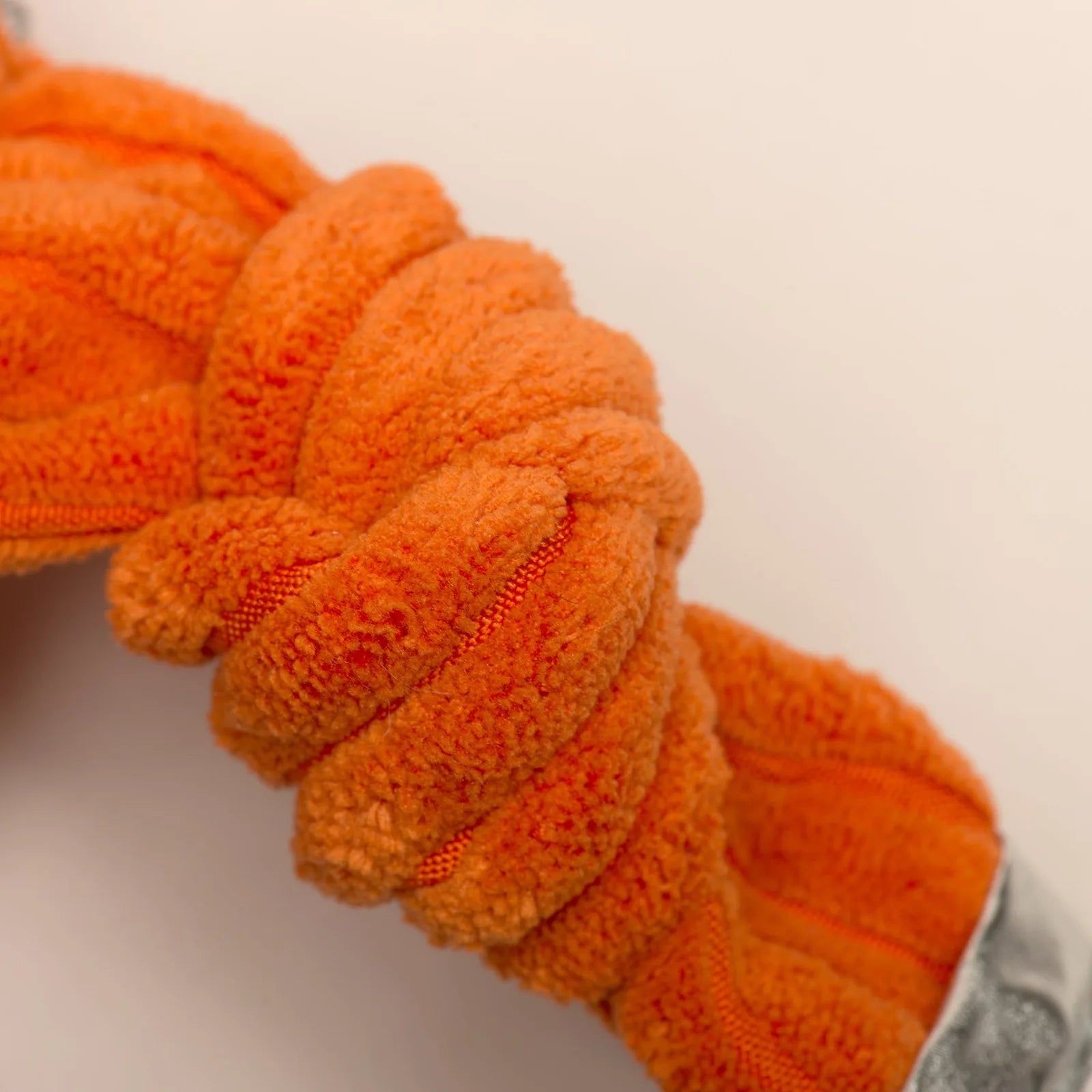 Bright orange, plush knotted dog toy from HuggleHounds, designed for tugging and snuggling playtime.