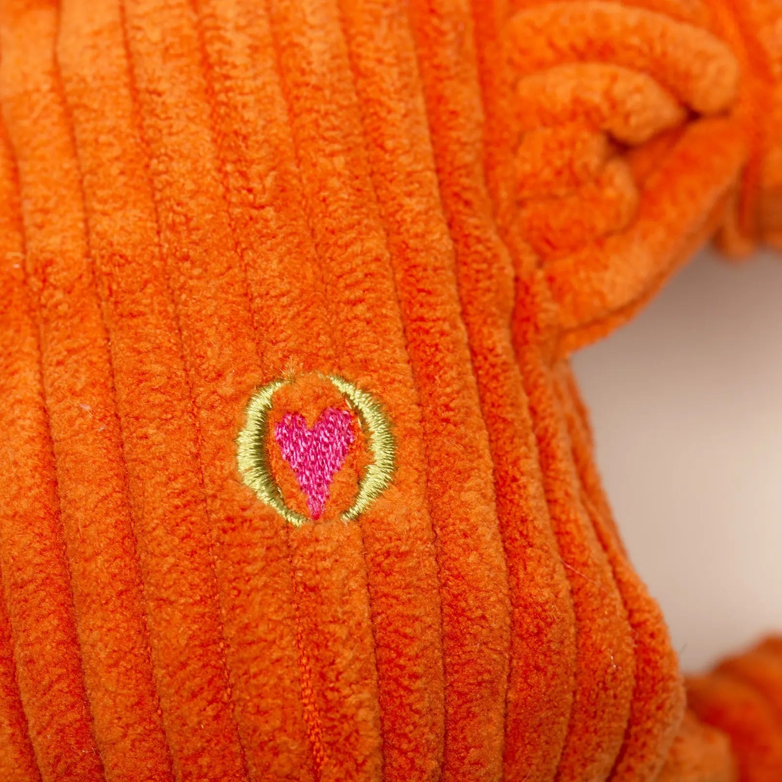 Bright orange Astro-Knottie® dog toy with ribbed texture and a pink heart emblem, perfect for cuddling and interactive play.