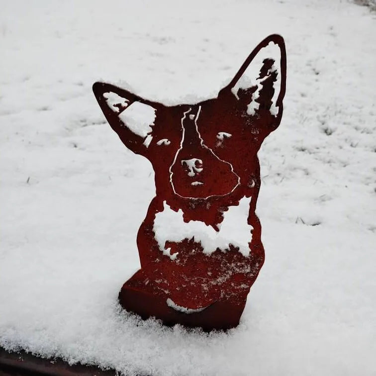 Australian Cattle Dog metal silhouette in weathered Corten steel with snow accents, ideal for outdoor decor.