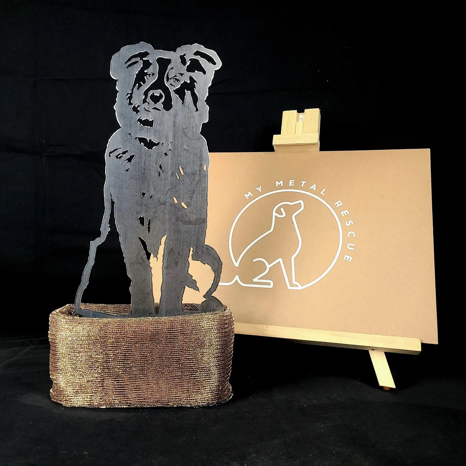 Australian Shepherd metal silhouette in black on a textured brown base, showcased against a plain background.