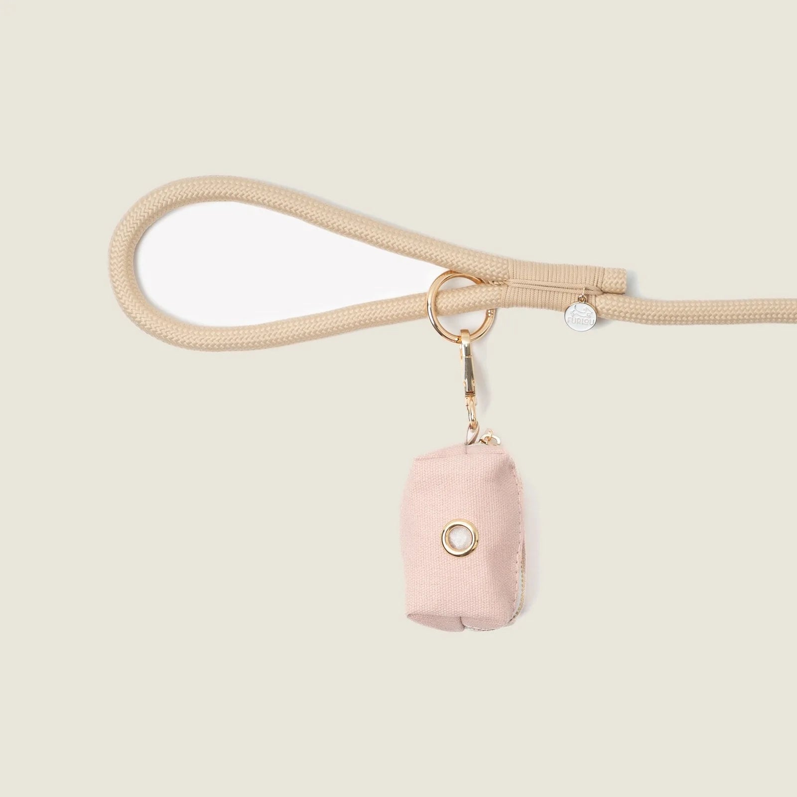 Baby pink poop bag holder by FURLOU, attached to a beige leash, offering stylish convenience for dog walking.