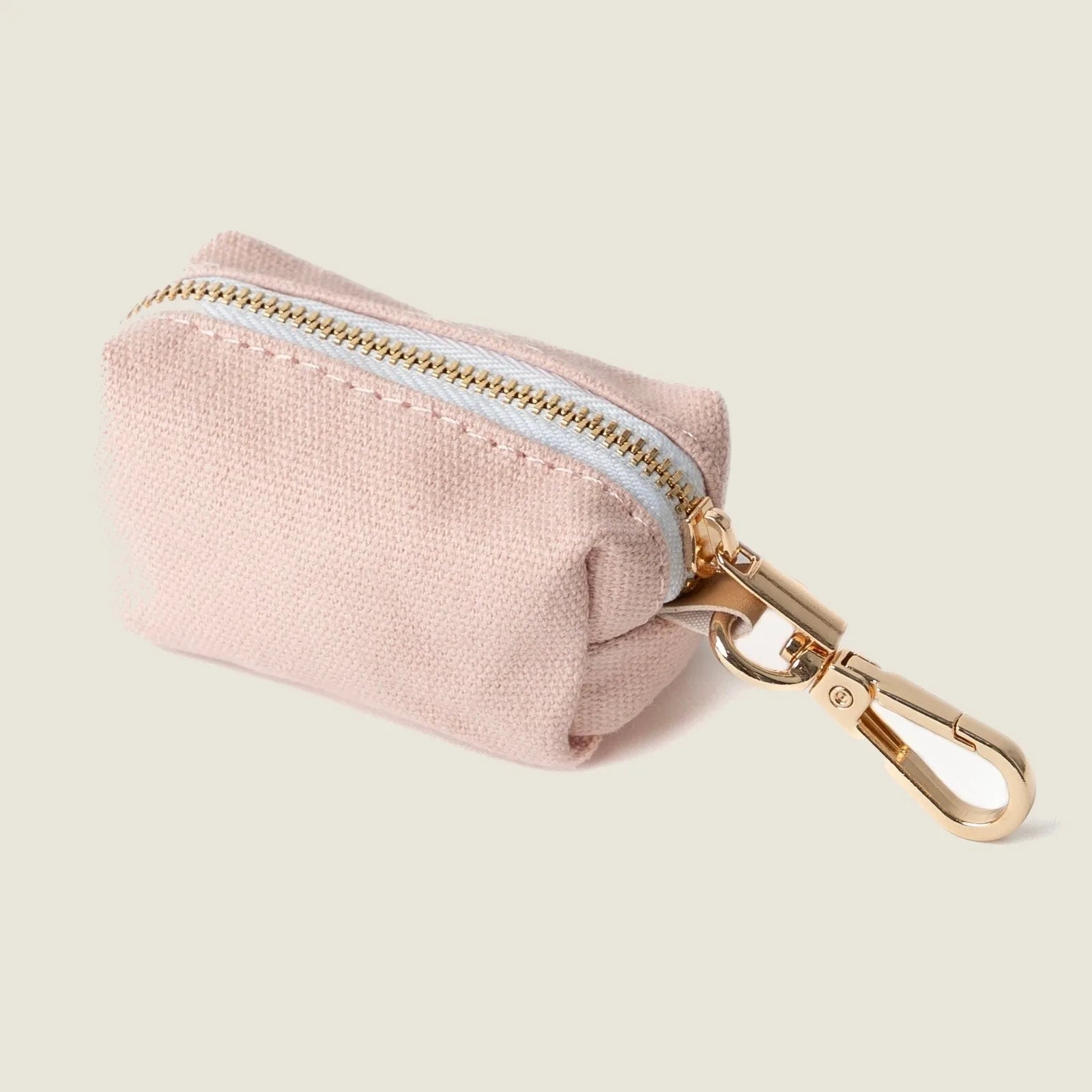 Soft baby pink poop bag holder with gold clip and zipper, perfect for walks with your dog.