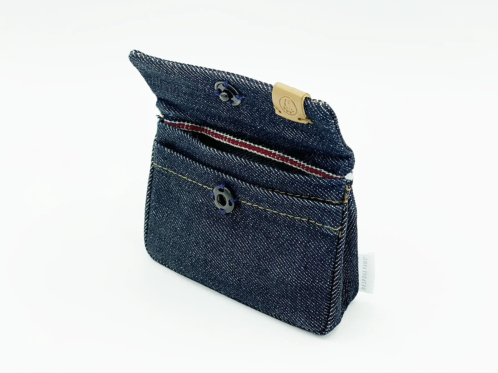 Compact denim waste bag dispenser with a card holder, featuring a button closure and contrast stitching.