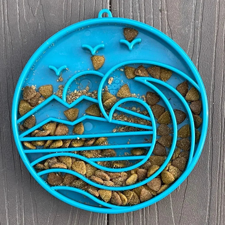 Shallow blue dog bowl with a wave design, featuring raised ridges and scattered kibble for slow feeding.