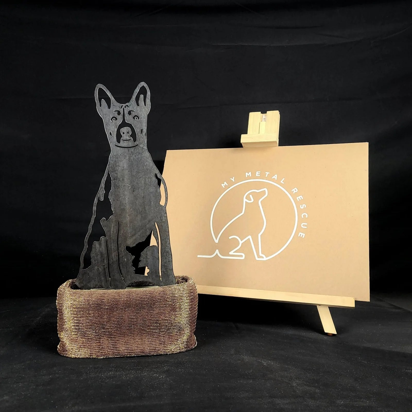Basenji metal silhouette in black, displayed in a rustic holder, alongside a My Metal Rescue sign.