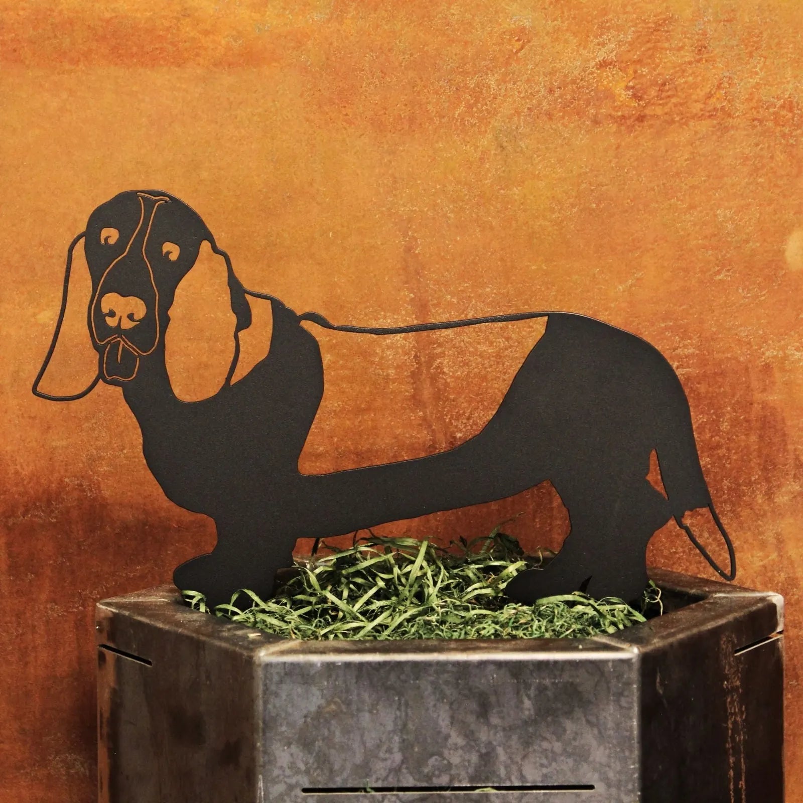 Black Basset Hound metal silhouette on a decorative base with green grass, showcasing its playful design and sturdy material.