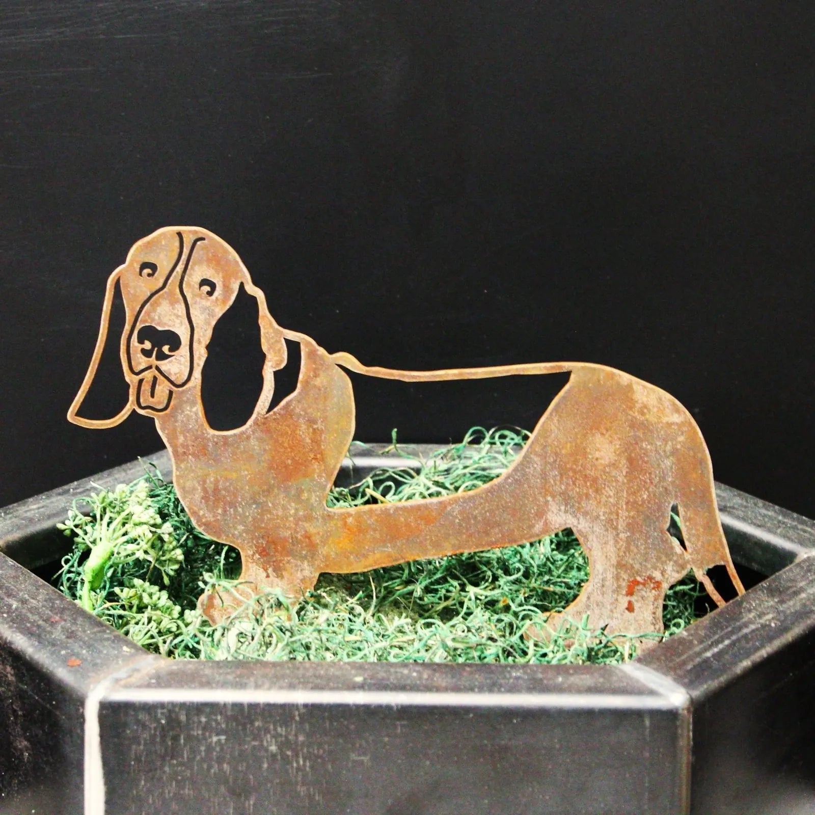 Rustic Basset Hound silhouette made of Corten steel, displaying a natural rust patina, set in green moss decor.