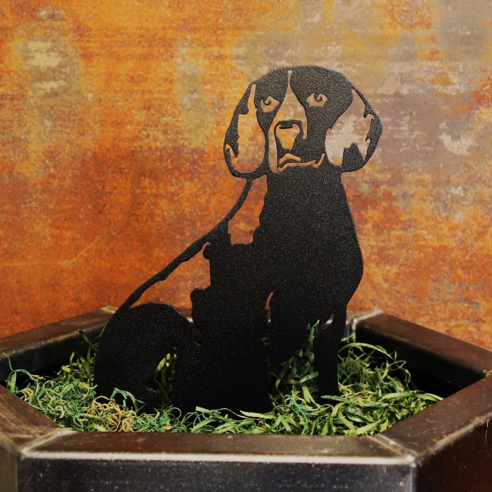 Black metal Beagle silhouette sitting in a decorative planter with green shredded paper, adding rustic dog decor charm.
