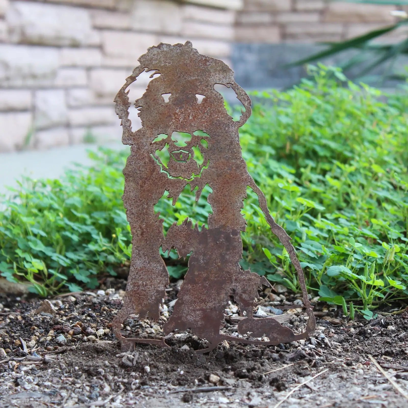 Rusty Corten steel silhouette of a Bearded Collie, displayed outdoors among greenery, adding rustic charm to the garden.