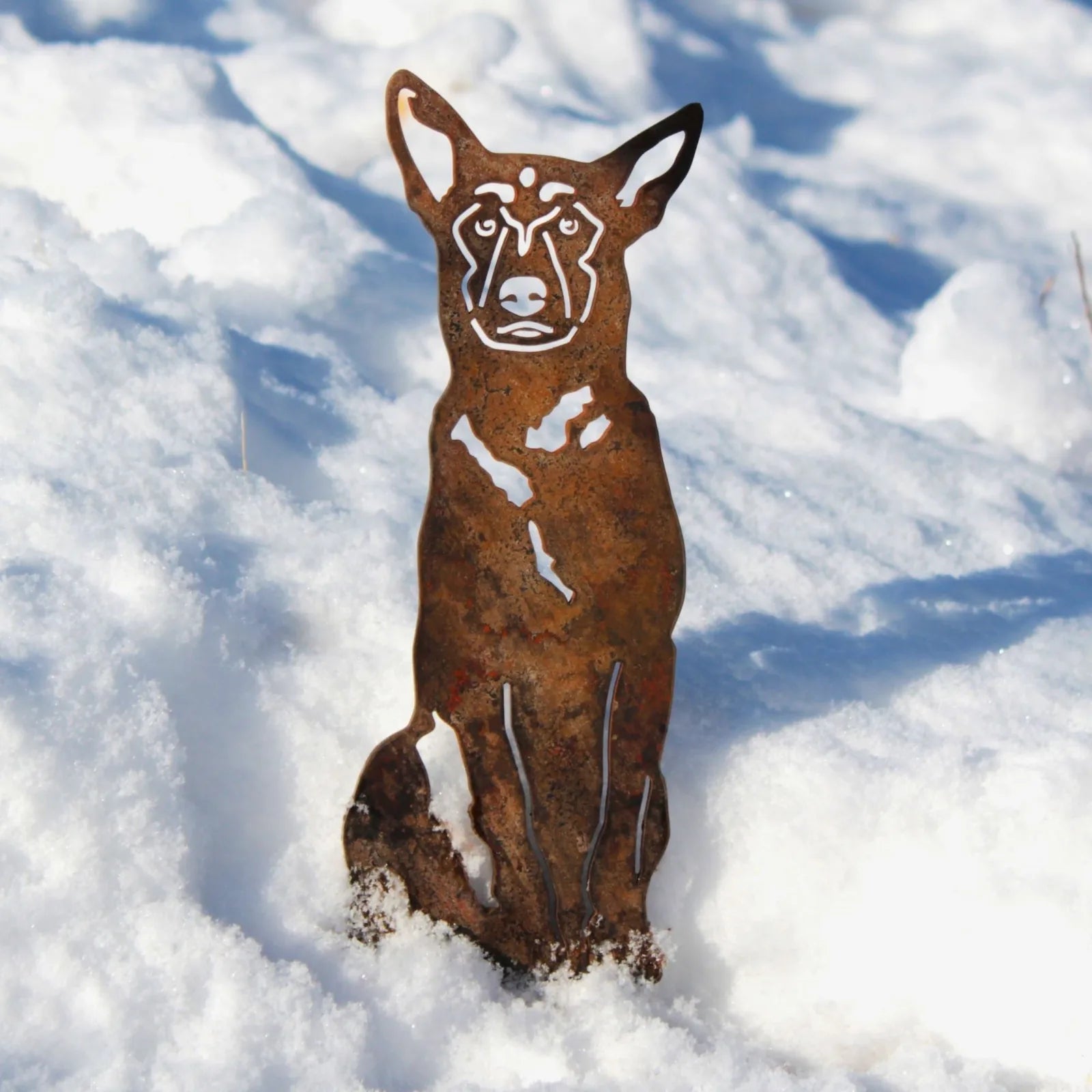 Belgian Malinois silhouette in weathered Corten steel, beautifully set against a snowy background.