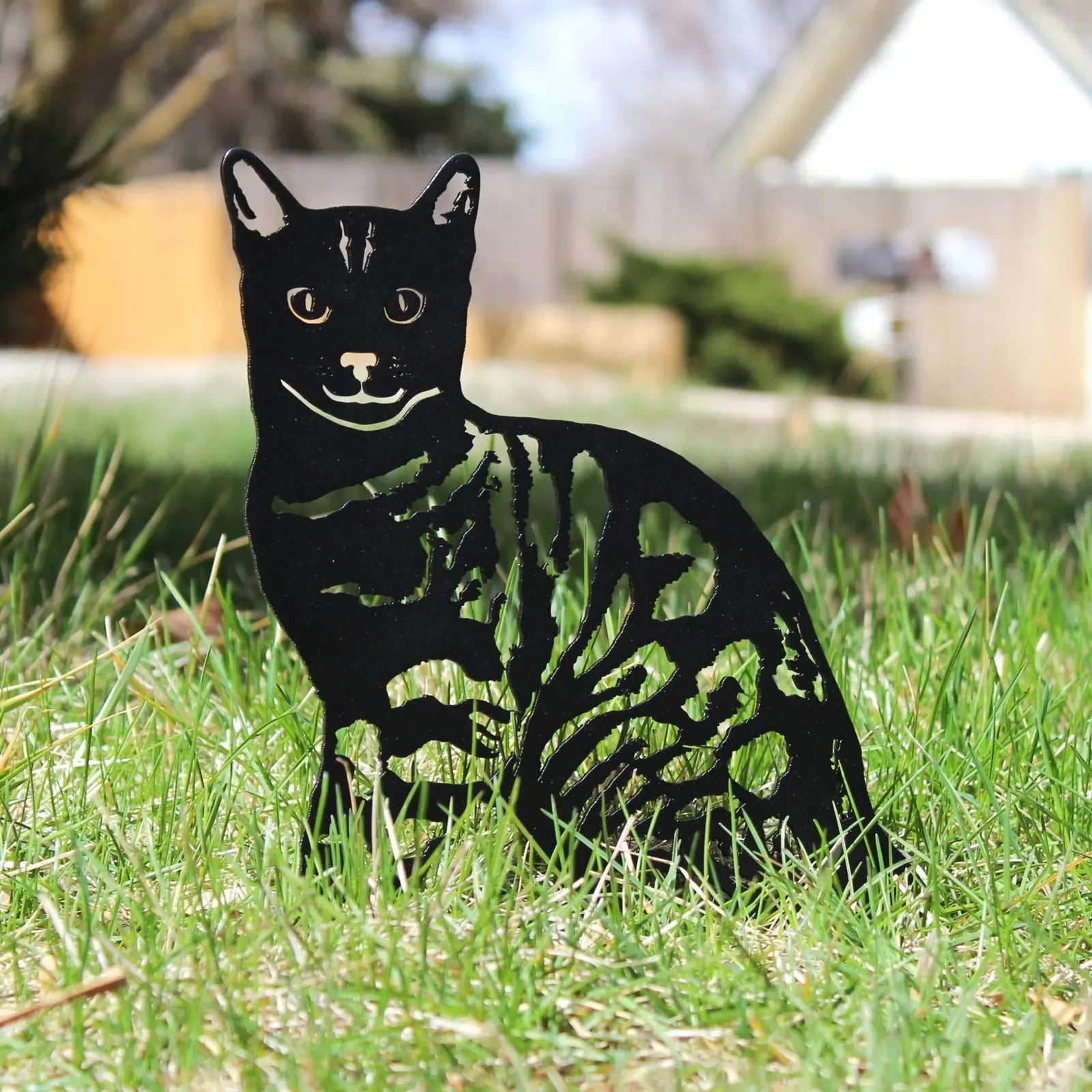 Black Bengal metal silhouette sculpture on grass, showcasing intricate cutouts and a playful design.