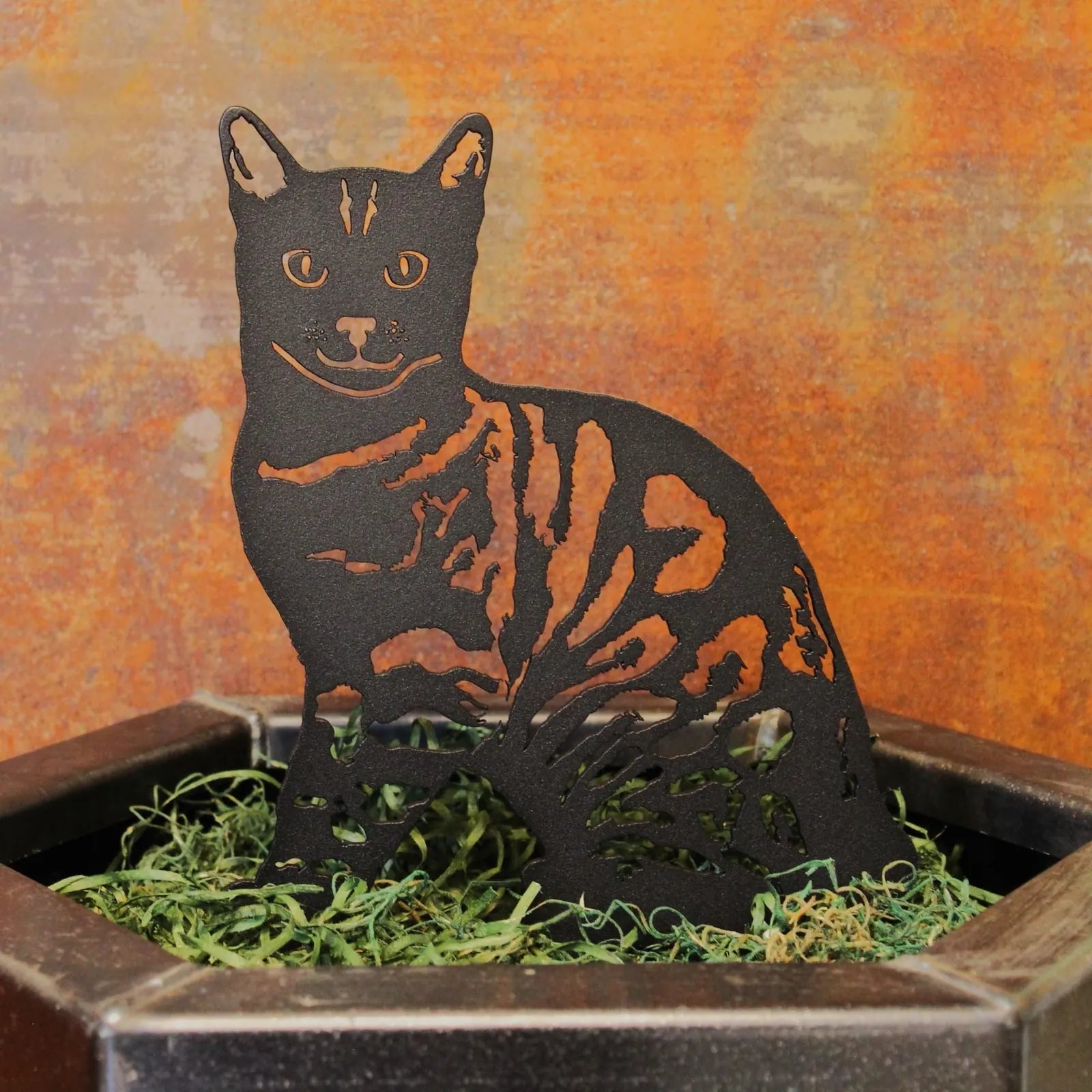 Black Bengal cat silhouette made from sturdy metal, showcasing intricate cutouts, displayed in a textured container.