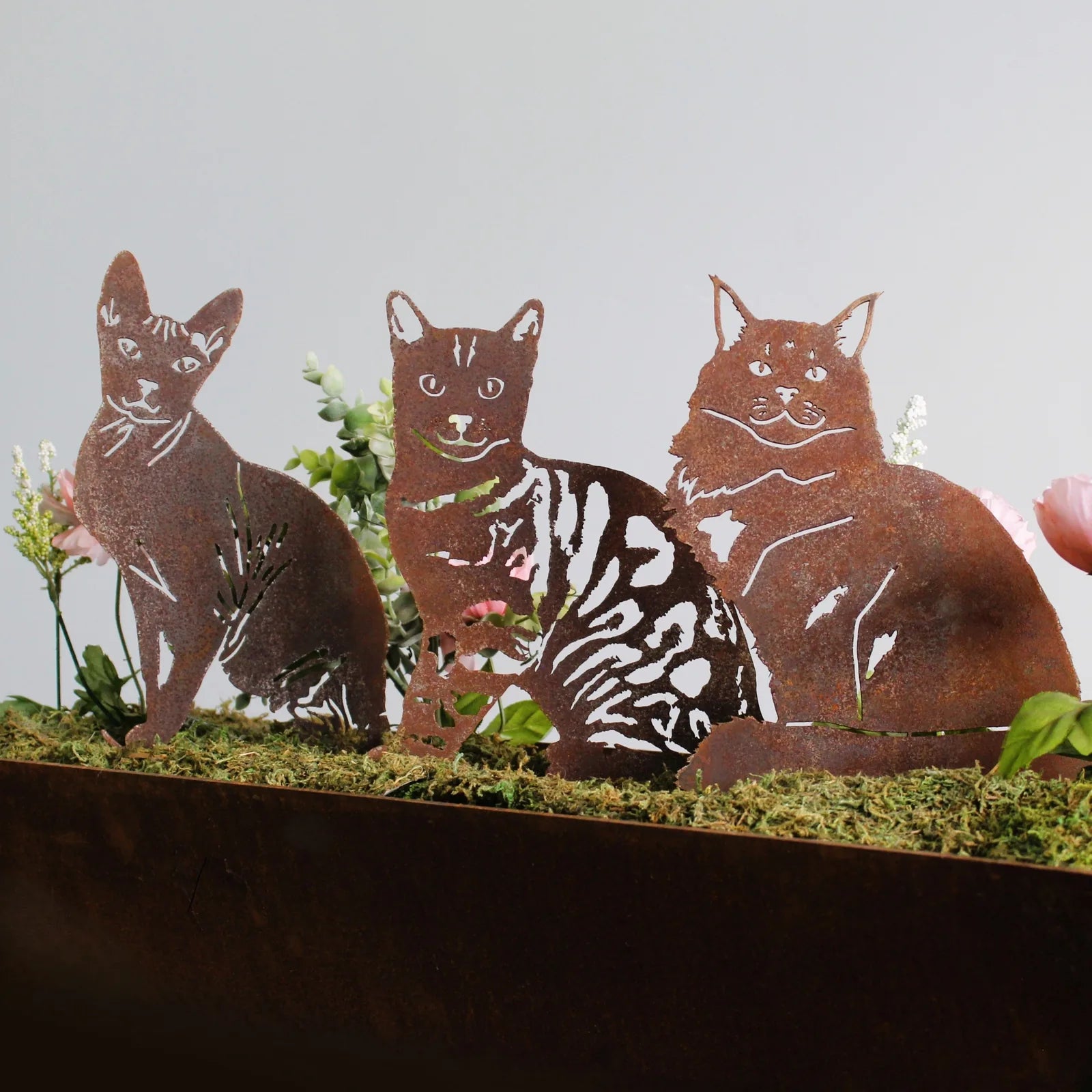 Handmade Bengal metal silhouette decor in rusted Corten steel featuring three cat designs amidst flower arrangements.