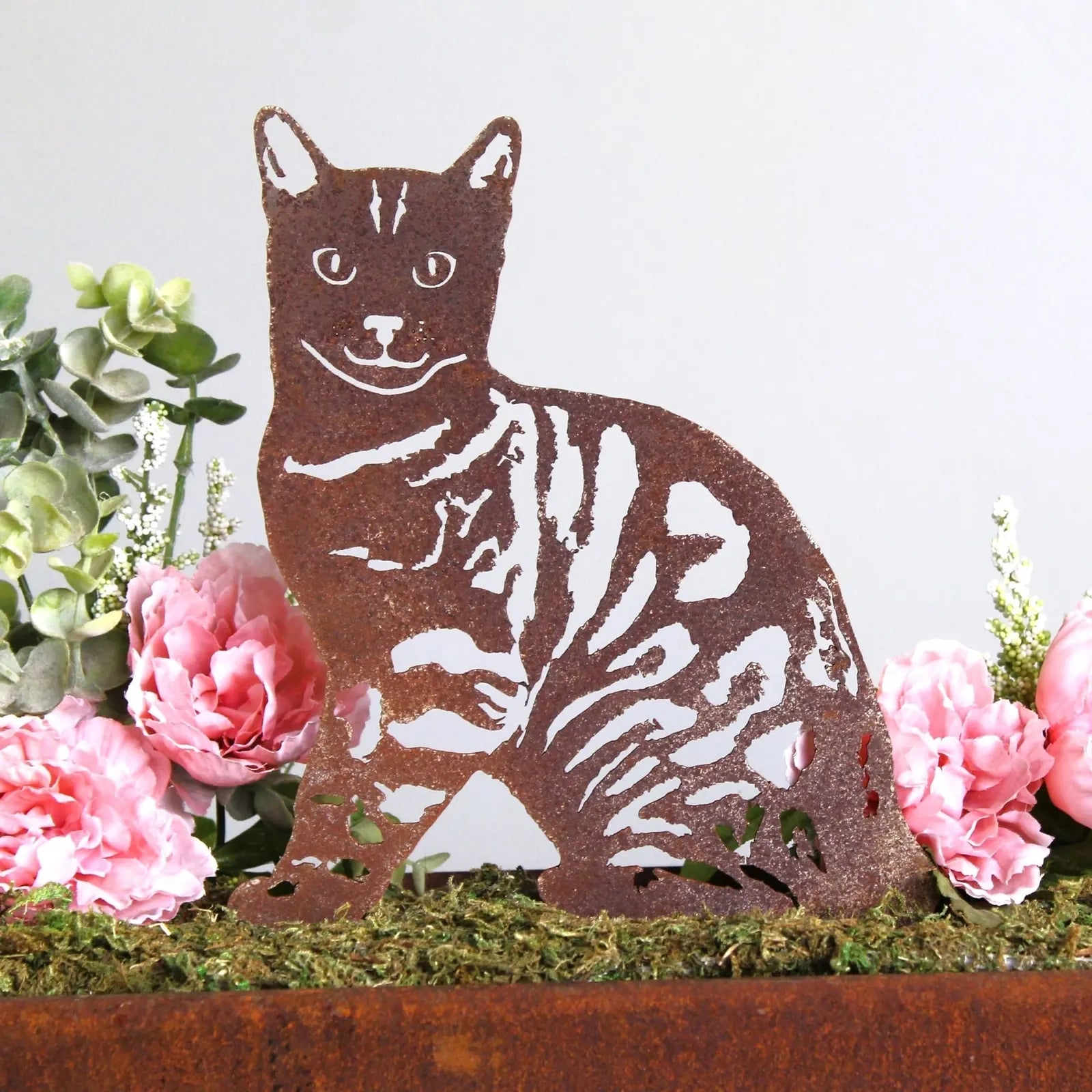 Bengal metal silhouette in rusted Corten steel beside pink peonies and greenery, showcasing intricate design details.
