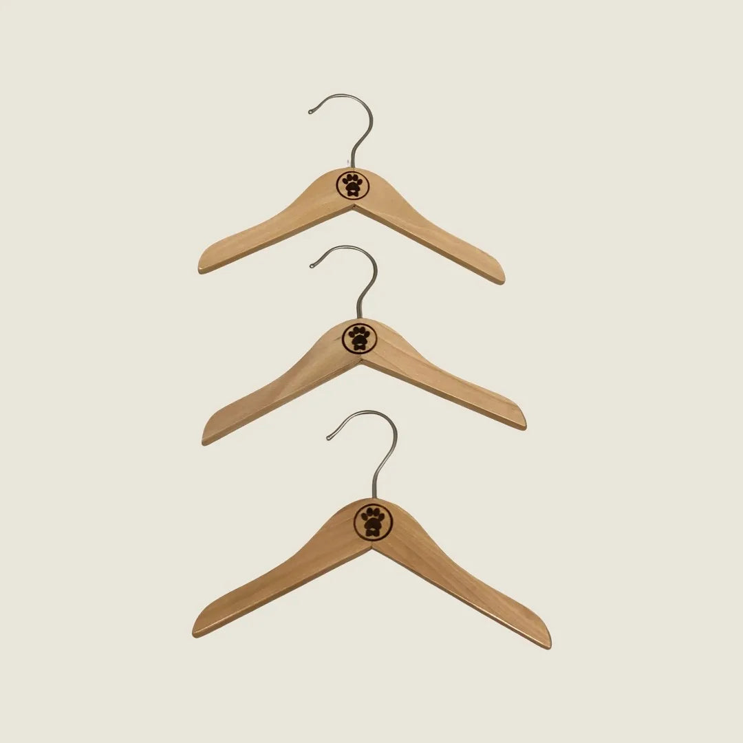 Three polished wooden hangers with metal hooks, featuring a paw print design on the top, organized vertically.