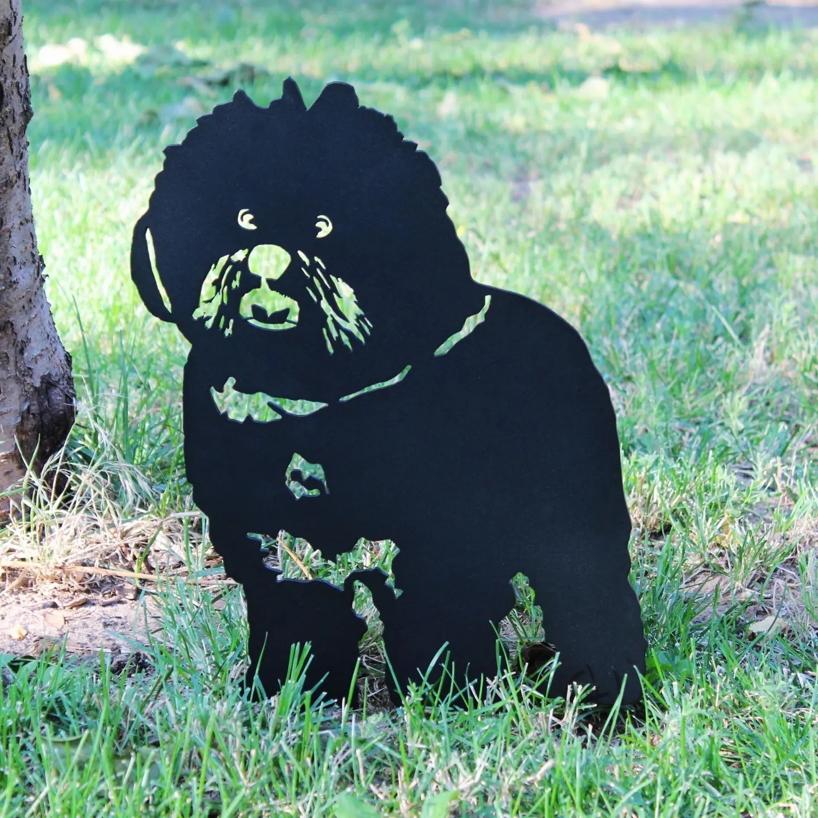 Black metal silhouette of a Bichon Frise dog among grass, showcasing a playful design for outdoor decor.