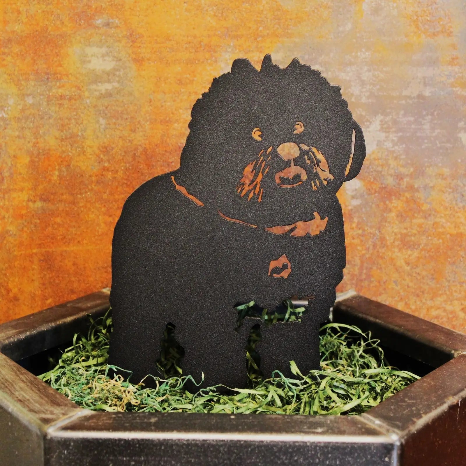 Bichon Frise silhouette in black metal, set in greenery, showcasing detailed craftsmanship and design.