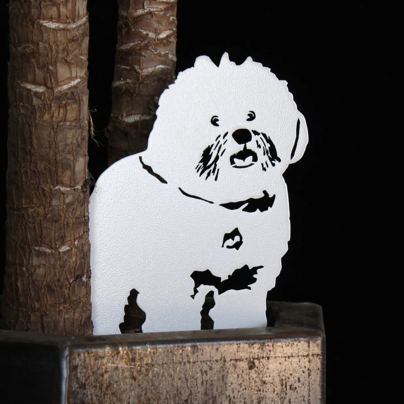 Handcrafted white metal silhouette of a Bichon Frise dog, showcasing detailed features against a dark background.