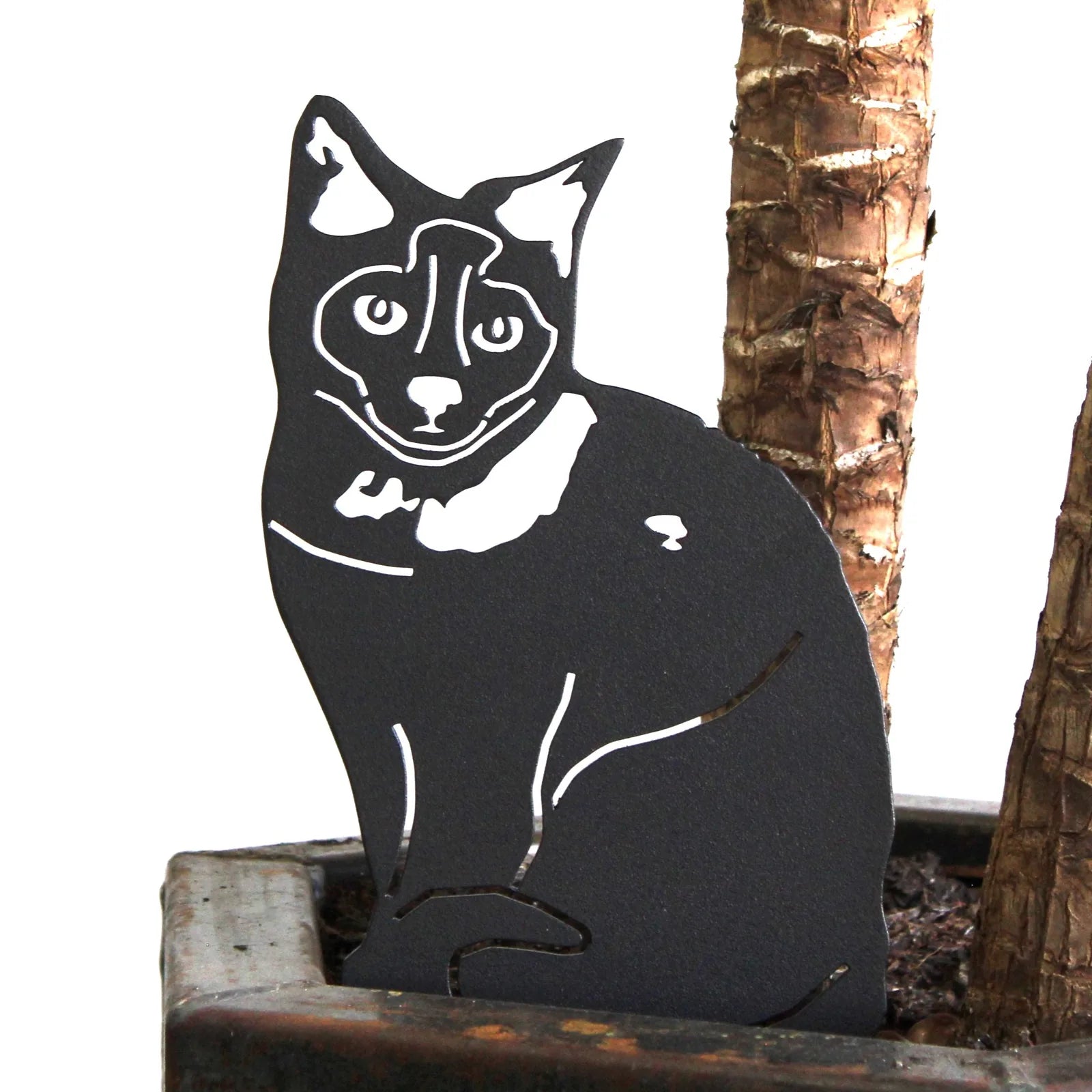 Black metal silhouette of a Birman dog, featuring intricate detailing, displayed in a potted plant.