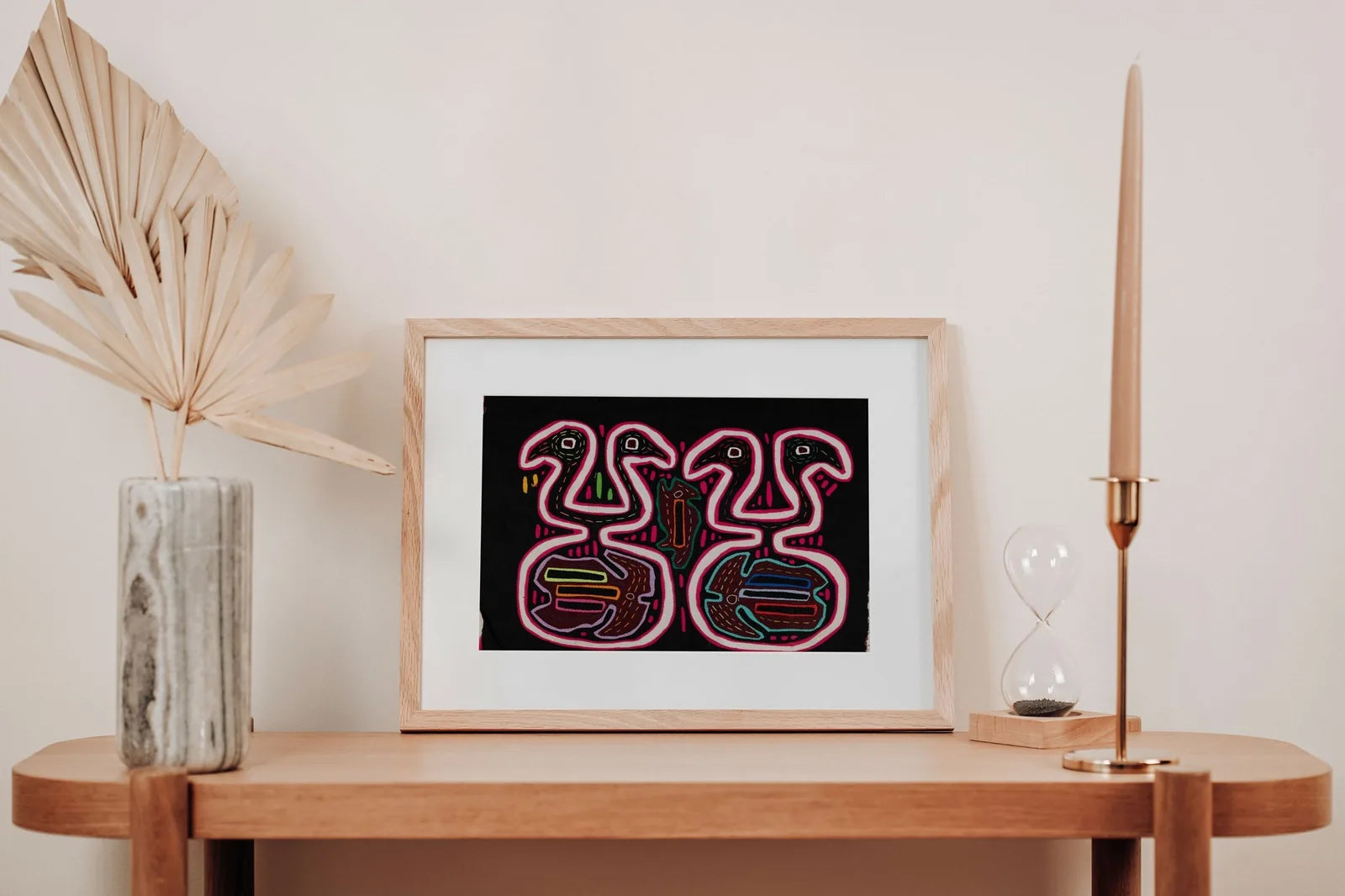 Black and pink optical illusion tapestry featuring hand-stitched geometric patterns by Guna artisans, framed with a natura...