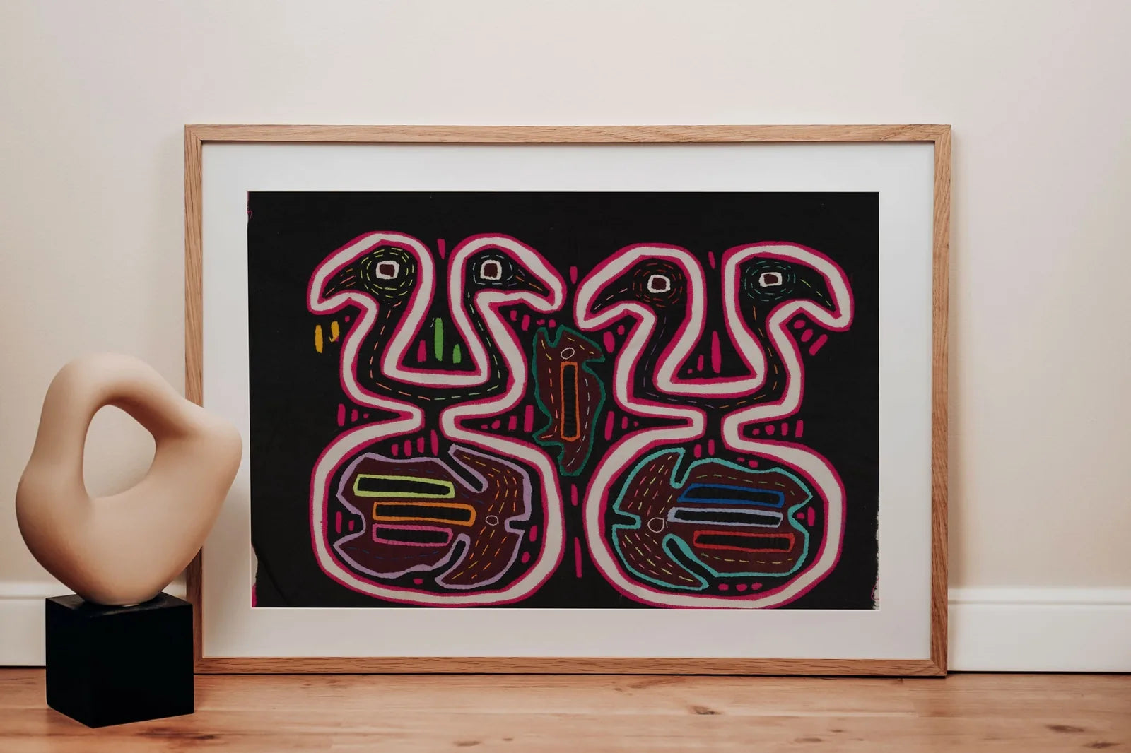 Black and pink optical illusion Mola tapestry featuring geometric patterns, hand-stitched by Guna artisans in Panama.
