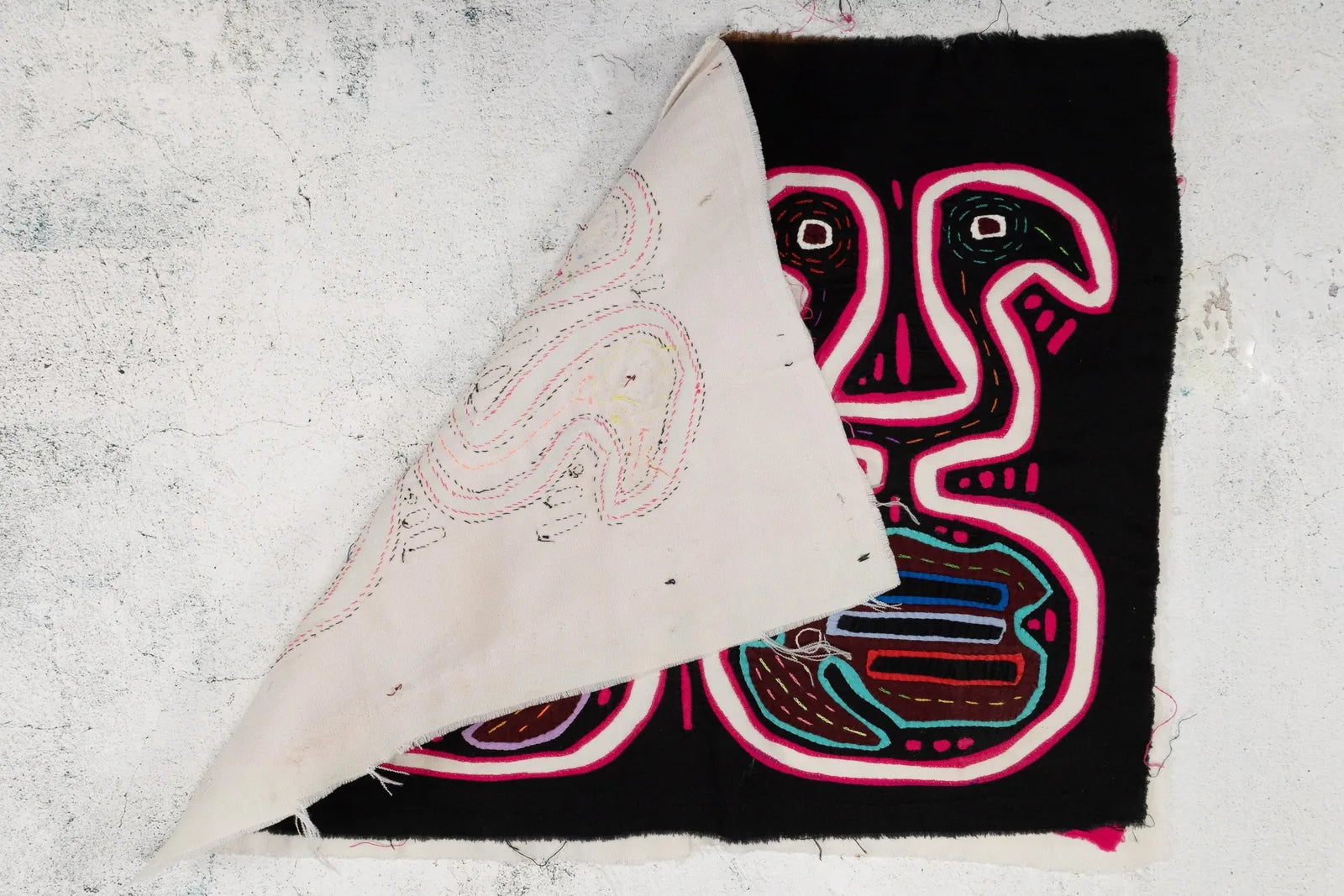 Black and pink optical illusion design featuring Guna-inspired motifs on a hand-stitched decorative tapestry.
