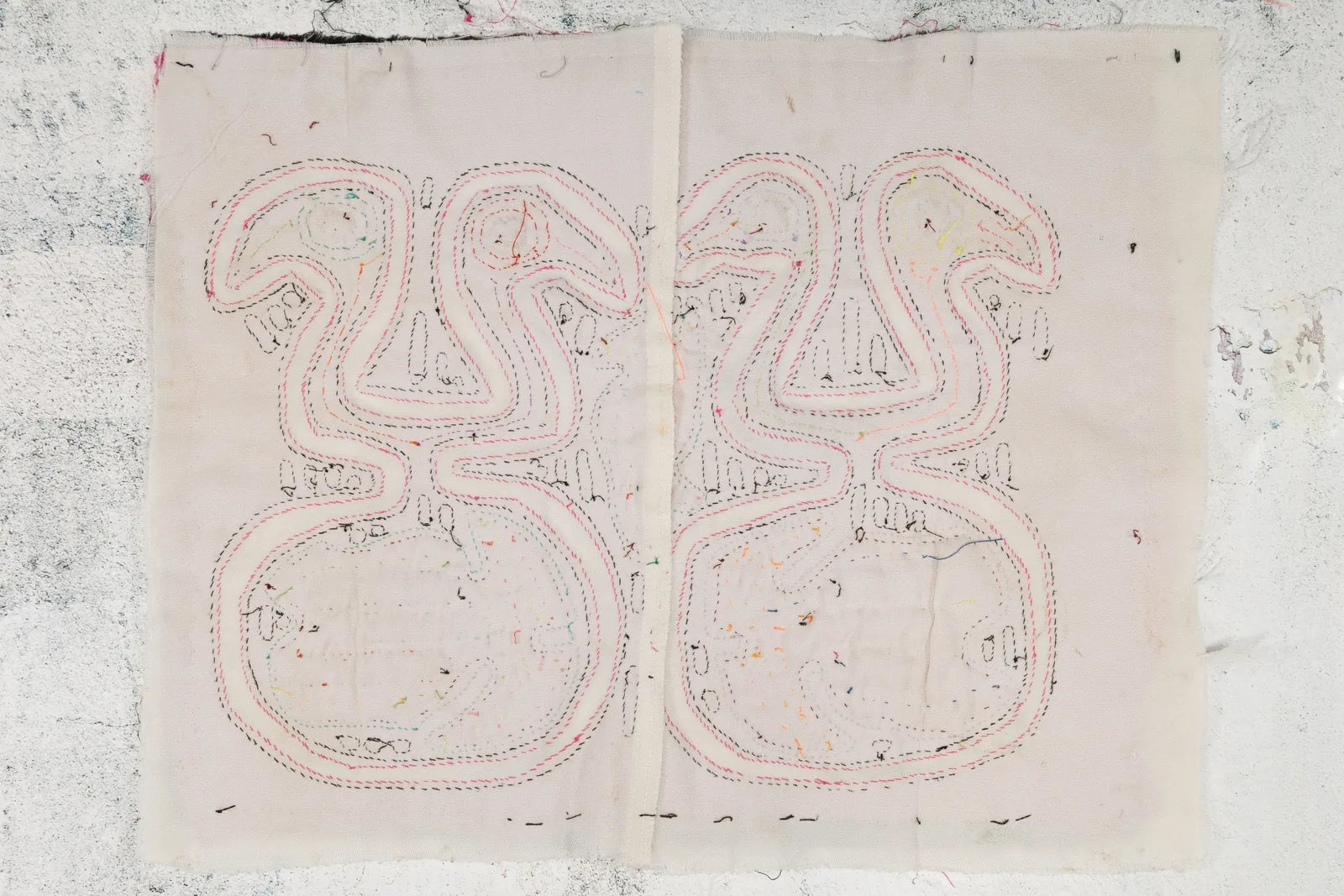 Hand-stitched black and pink geometric design on a soft cream backdrop, showcasing intricate Mola textile art.